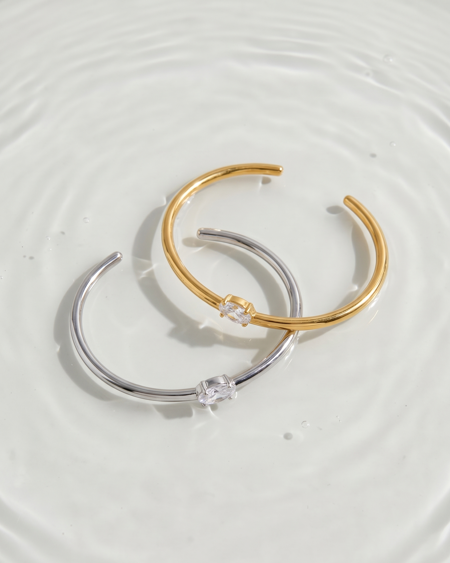Two gold and silver hoop earrings on a light gray background