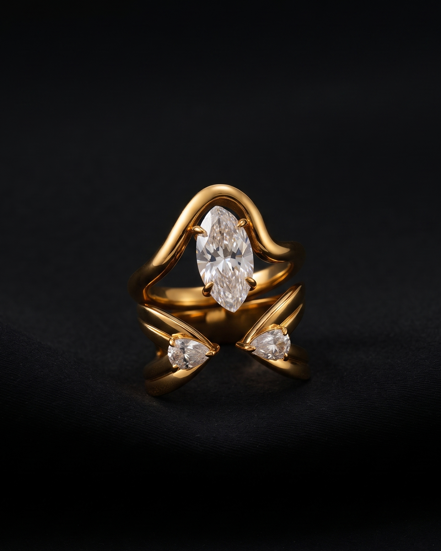 A gold ring featuring a marquise-cut clear center stone and two smaller marquise stones on the sides, set against a dark black background.