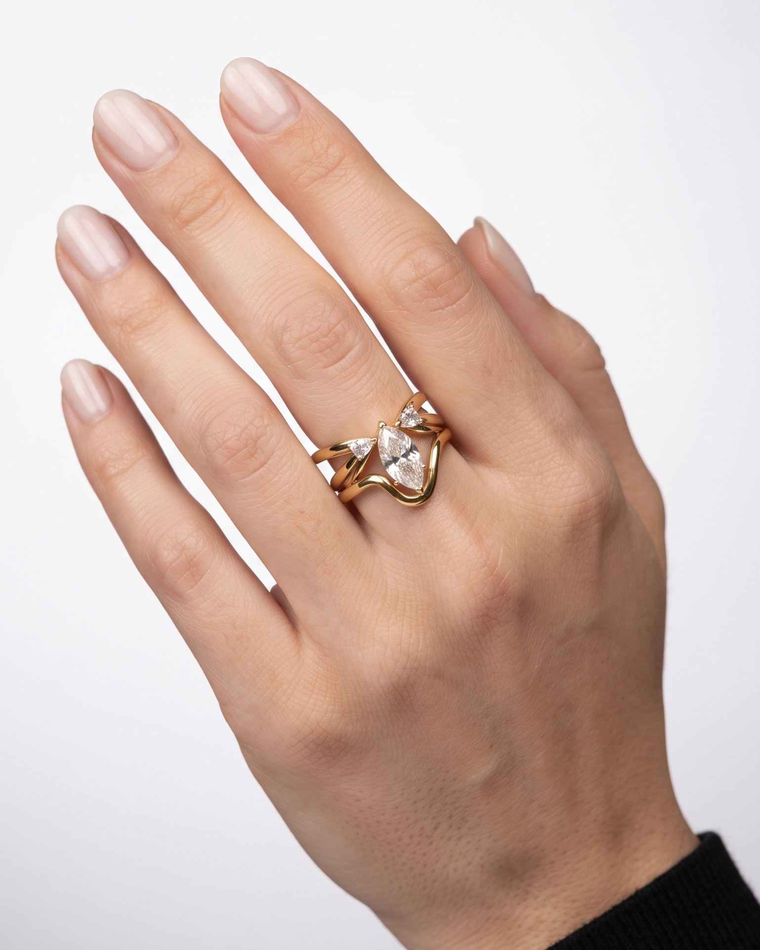 A gold ring with a heart-shaped clear gemstone and smaller clear stones, worn on a person's hand against a light gray background.