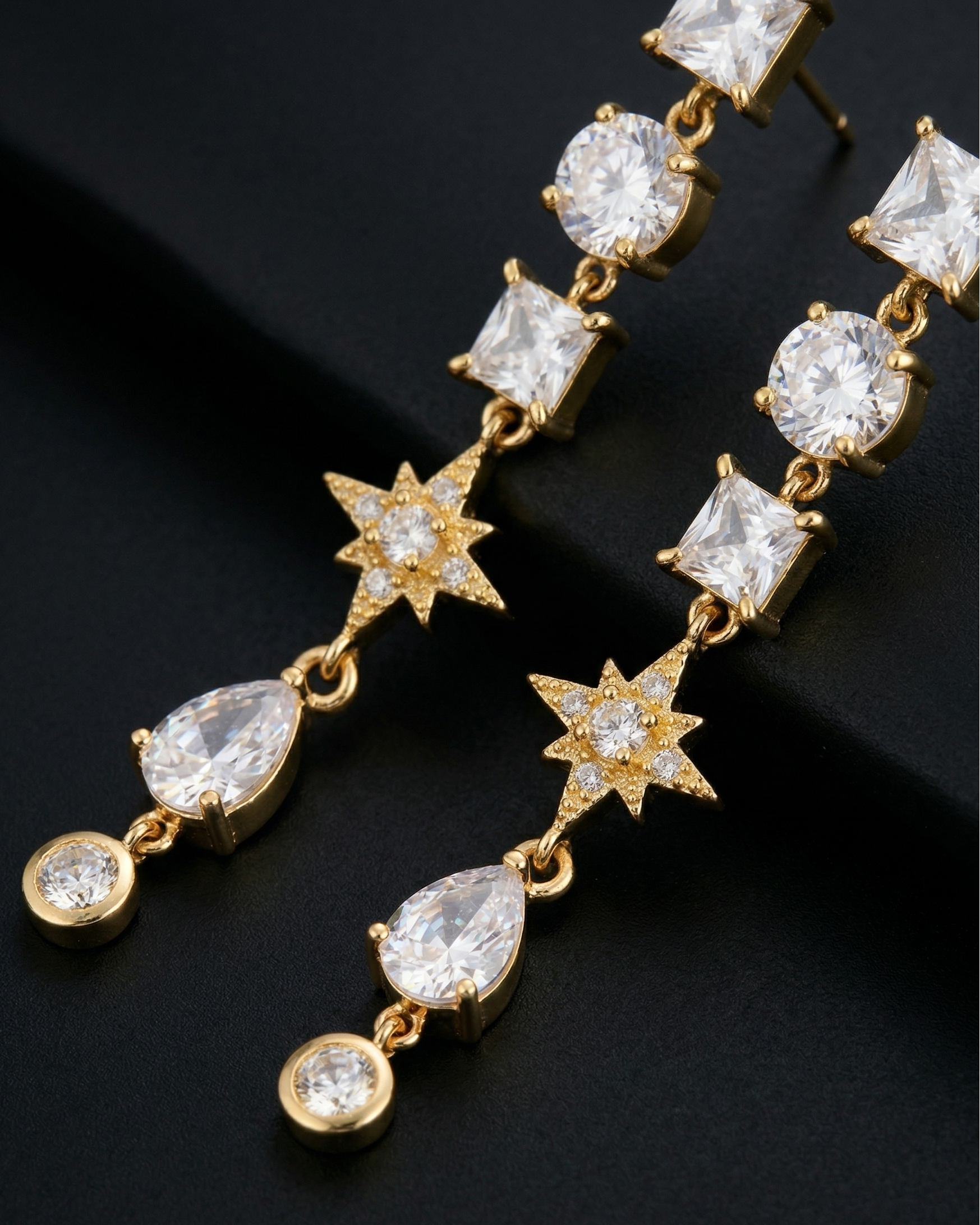 Gold earrings with clear gemstones on a black background