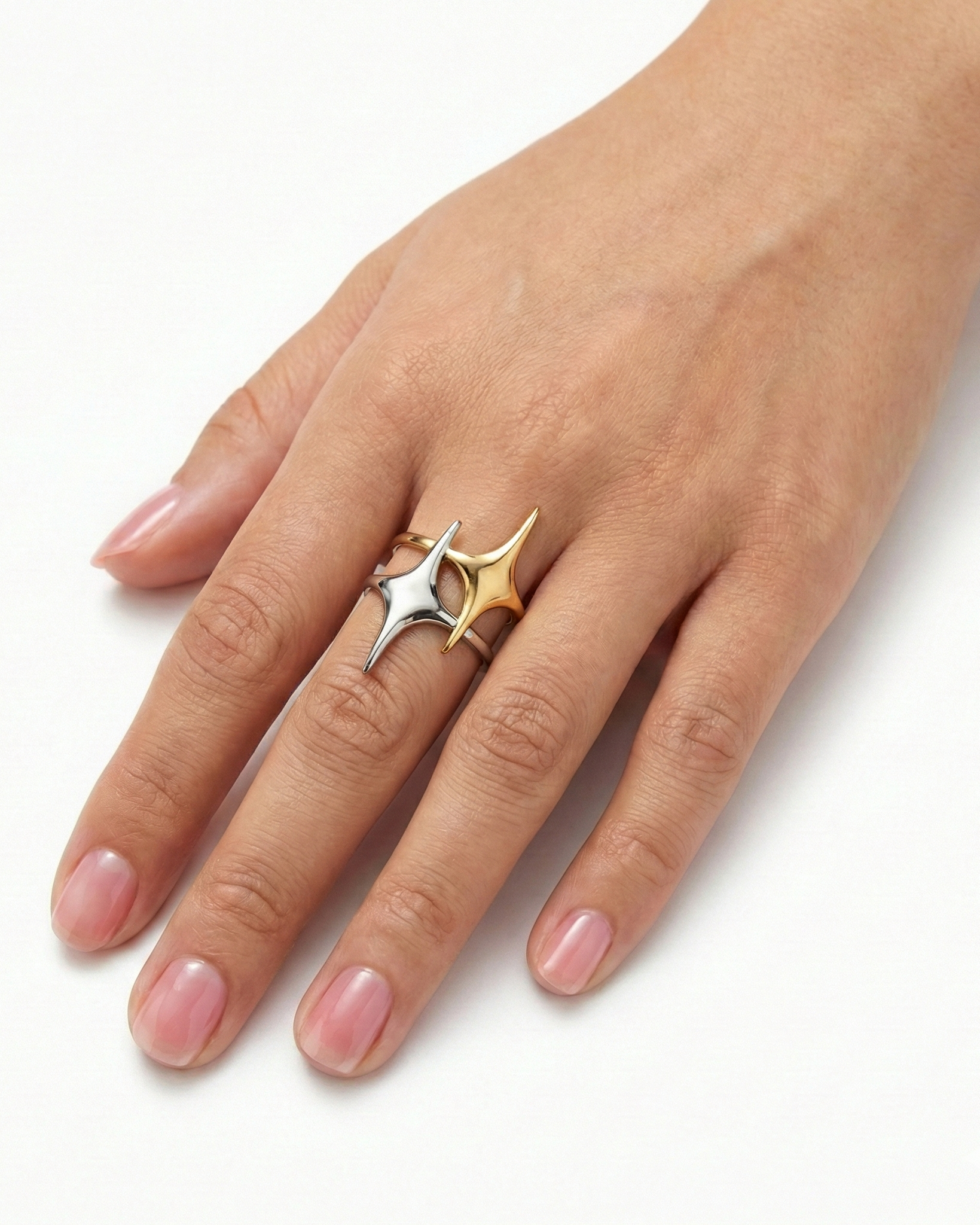 Hand wearing a two-tone ring with star design on a white background