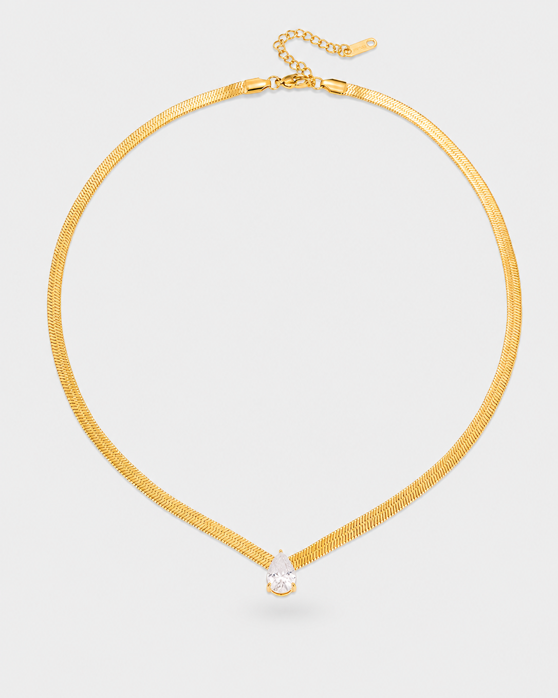 A gold snake chain choker necklace with a small teardrop-shaped clear gemstone pendant, displayed on a light gray background.