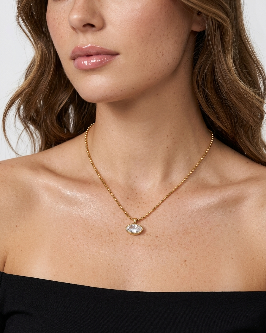 Close-up of a woman wearing a gold necklace with a pendant against a neutral background