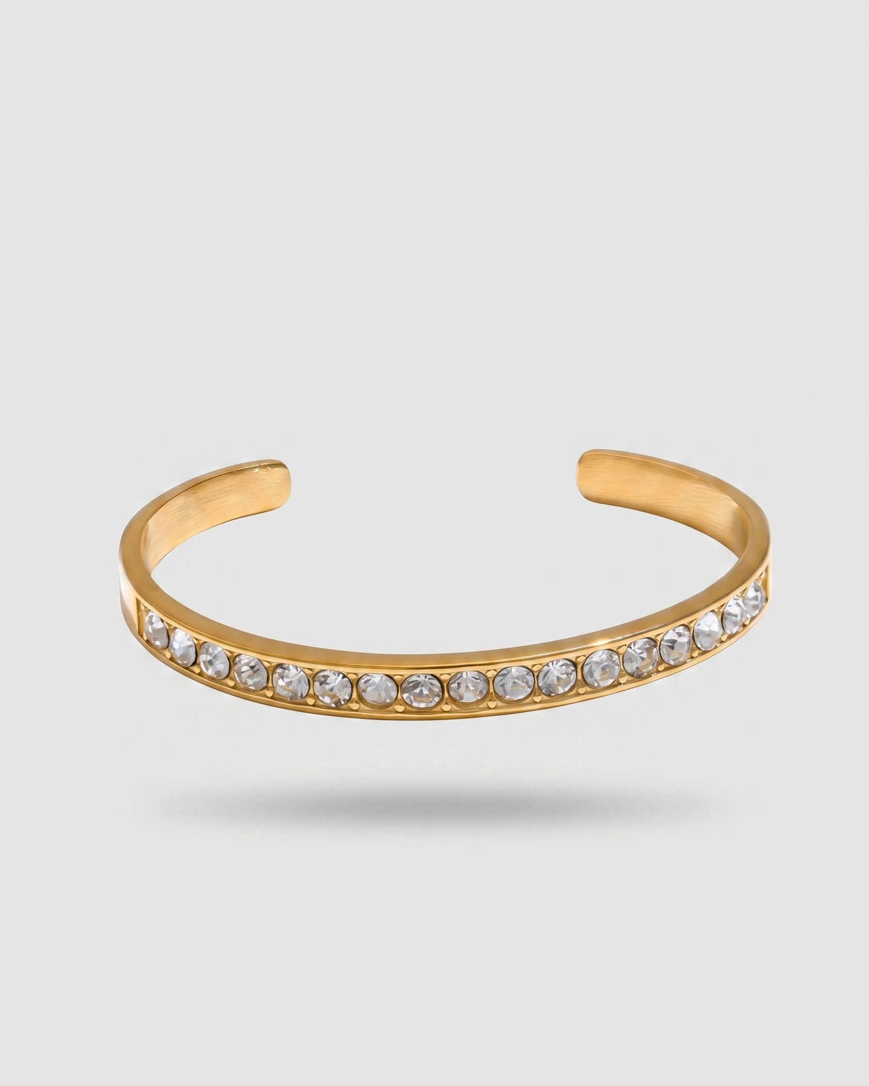 Gold bracelet with clear stones on a light gray background