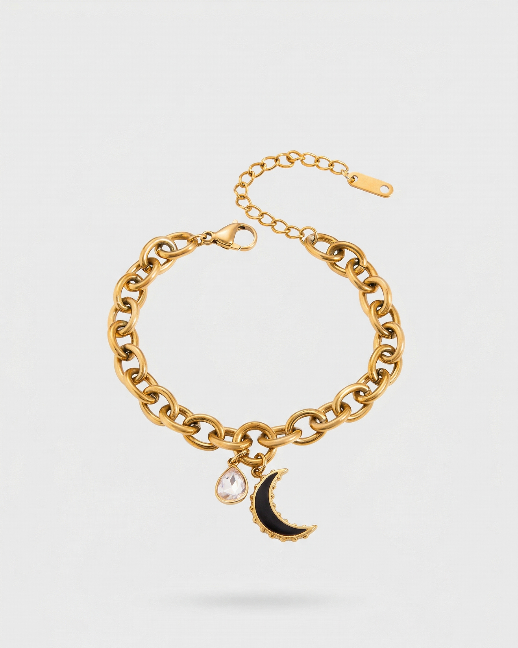 Gold chain bracelet with a moon charm on a light gray background