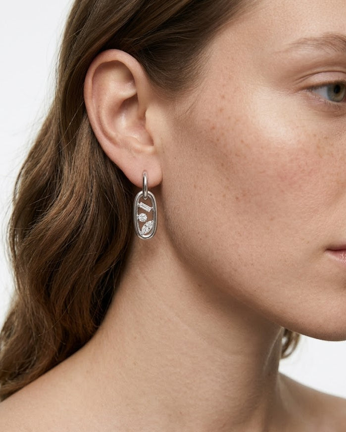 Close-up of a woman wearing a silver earring with a white background