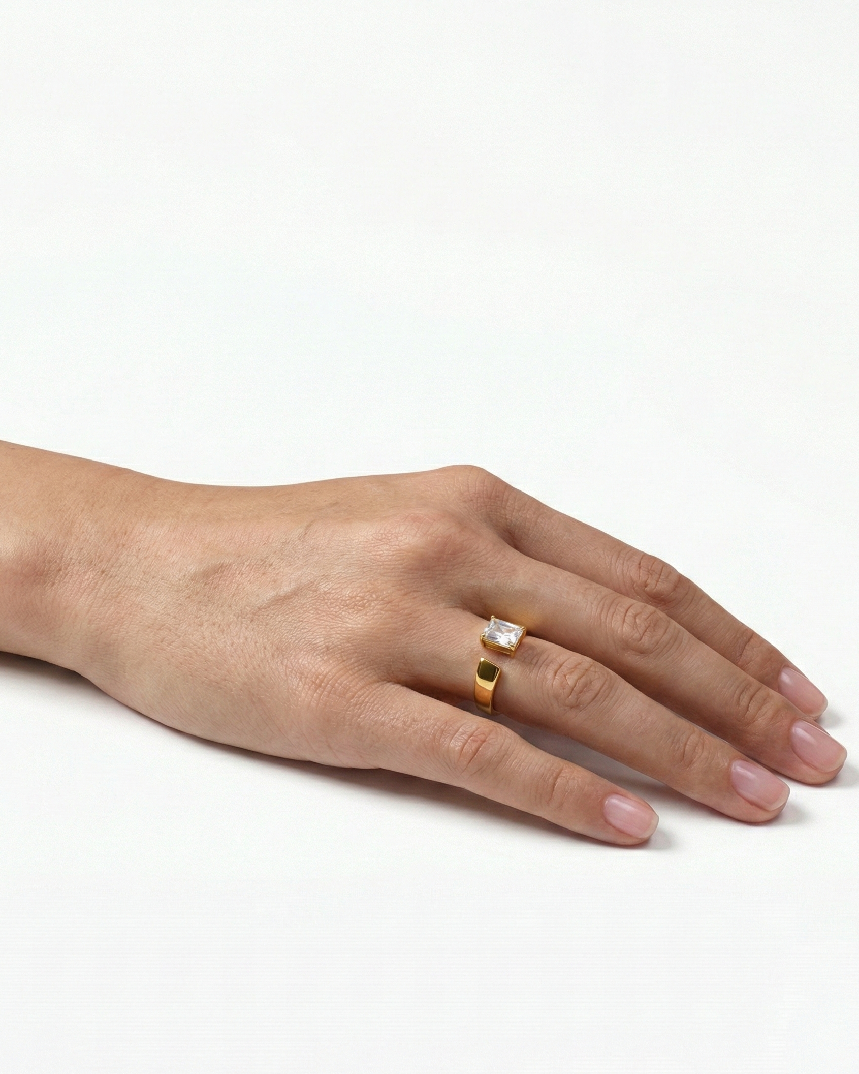 Hand wearing two rings on a white background