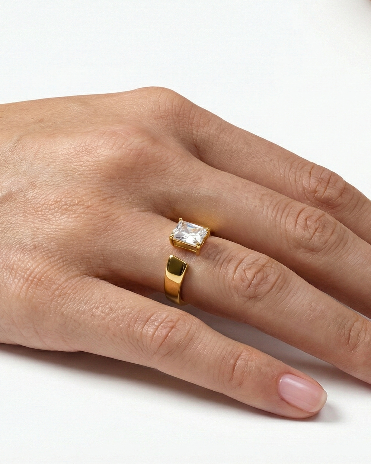 Hand wearing two rings on a white background