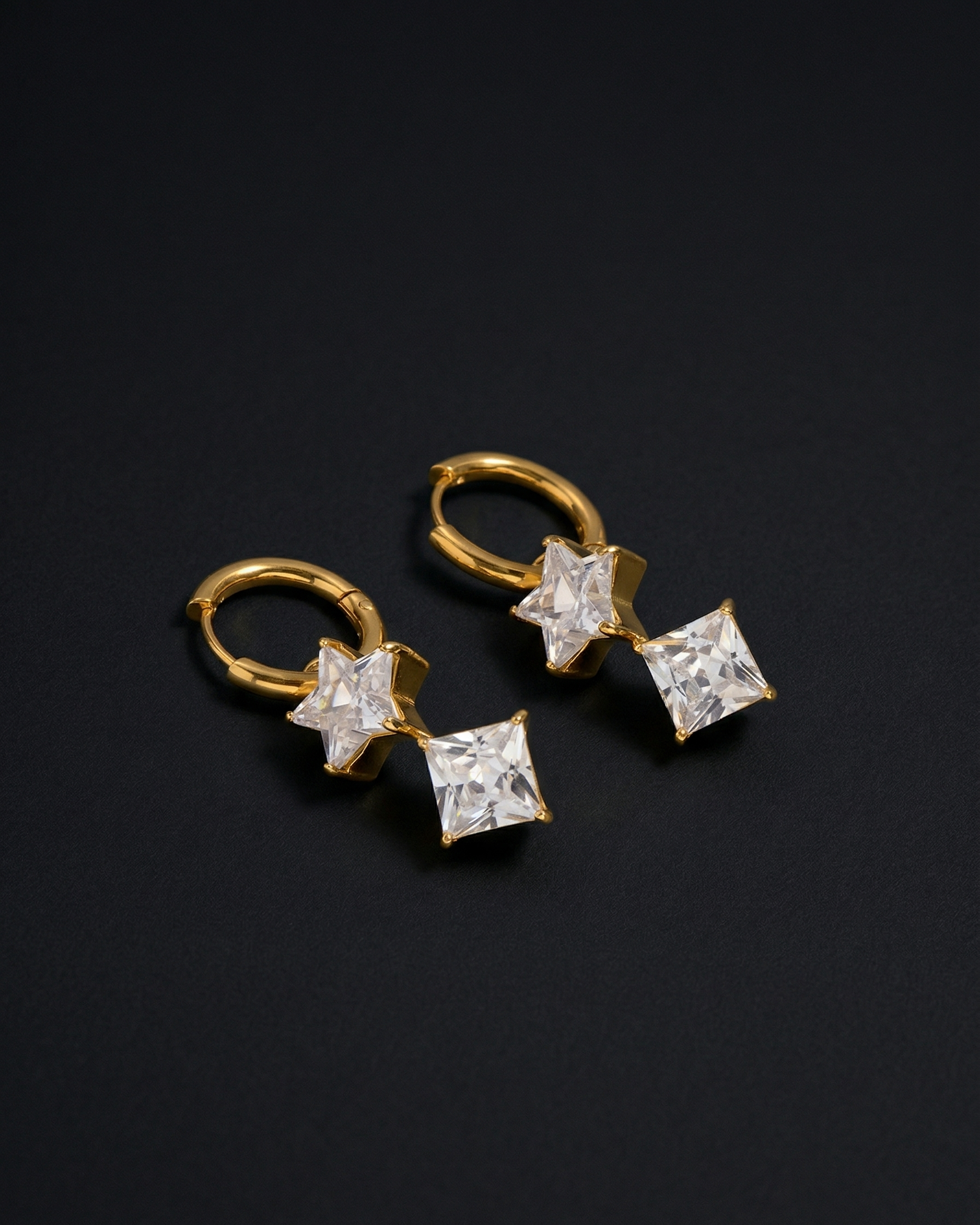 Gold earrings with star-shaped gemstones on a black background