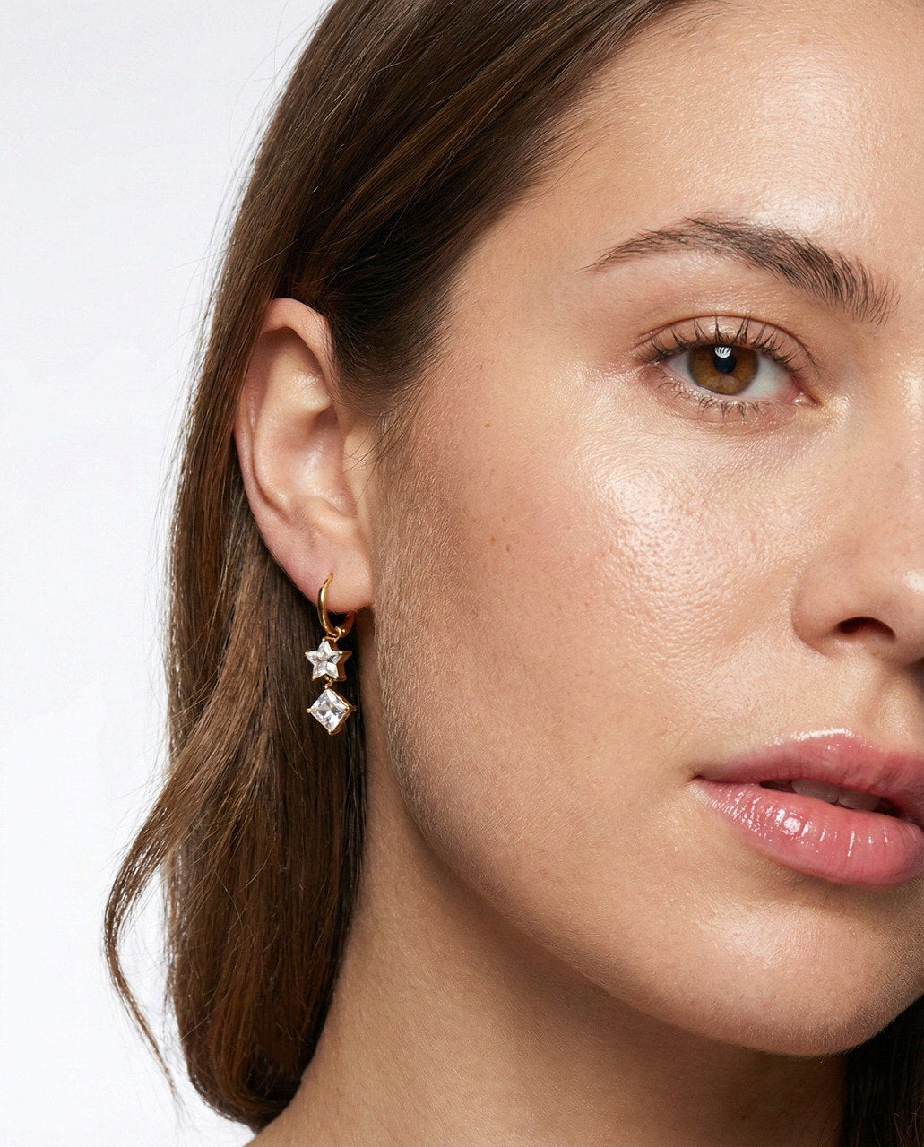 Close-up of a woman wearing star-shaped earrings with a neutral background