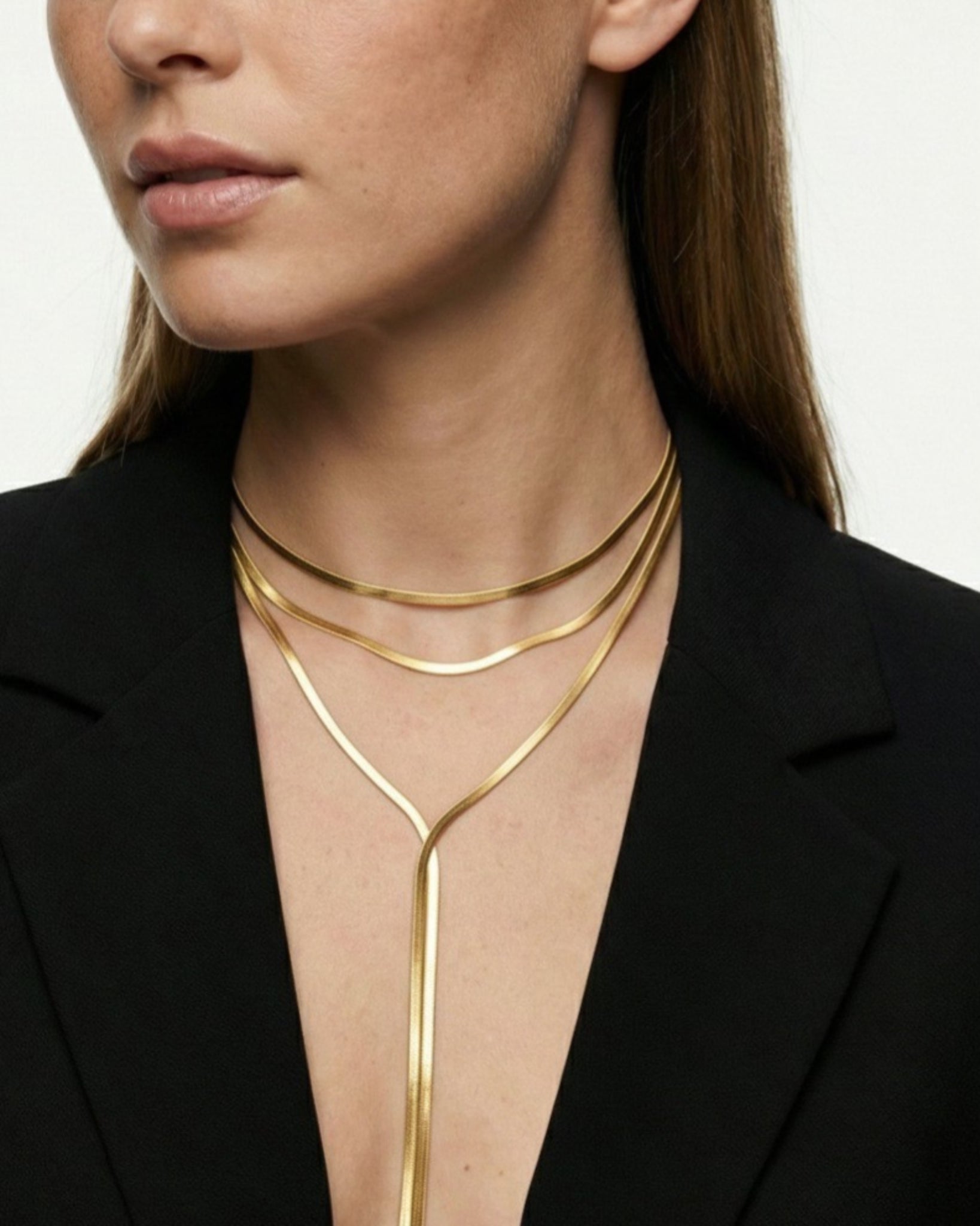 Woman wearing a gold neckpiece against a neutral background