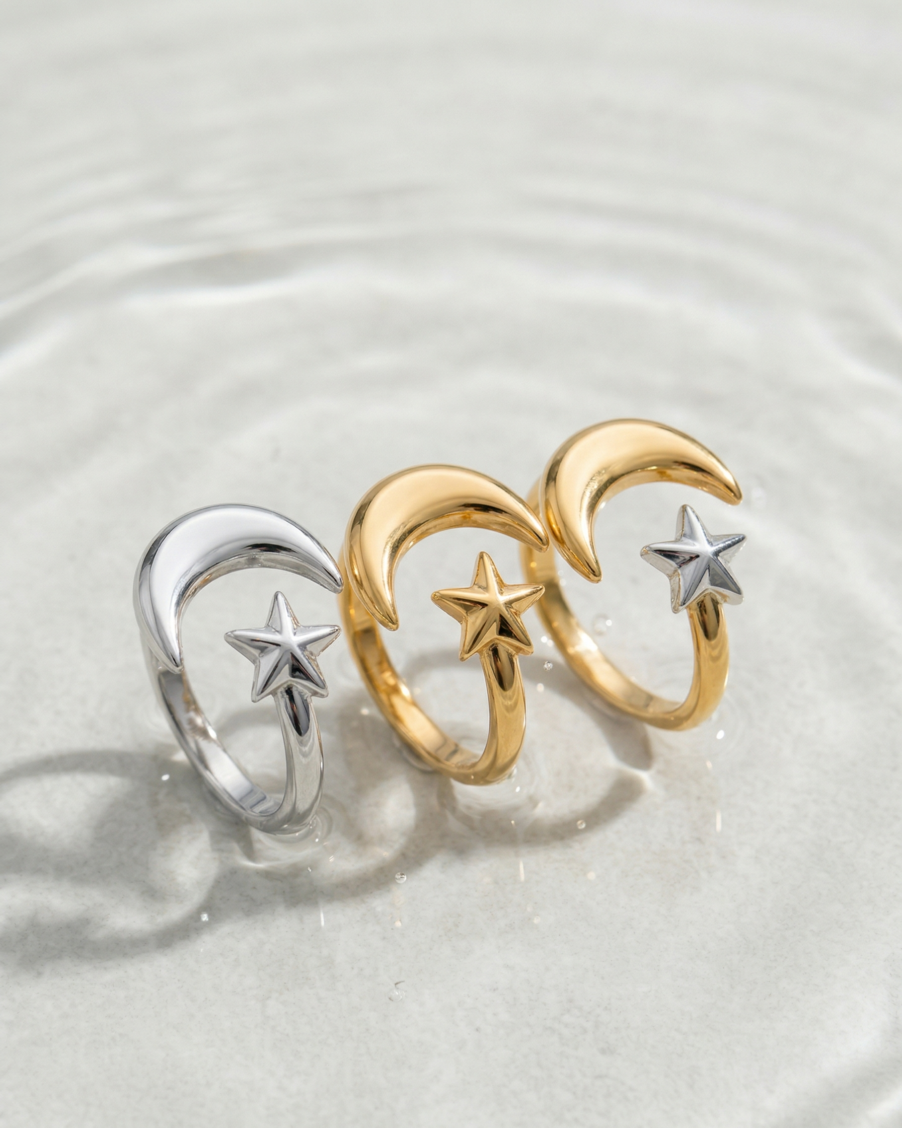 Two gold and silver rings with star and moon designs on a white background