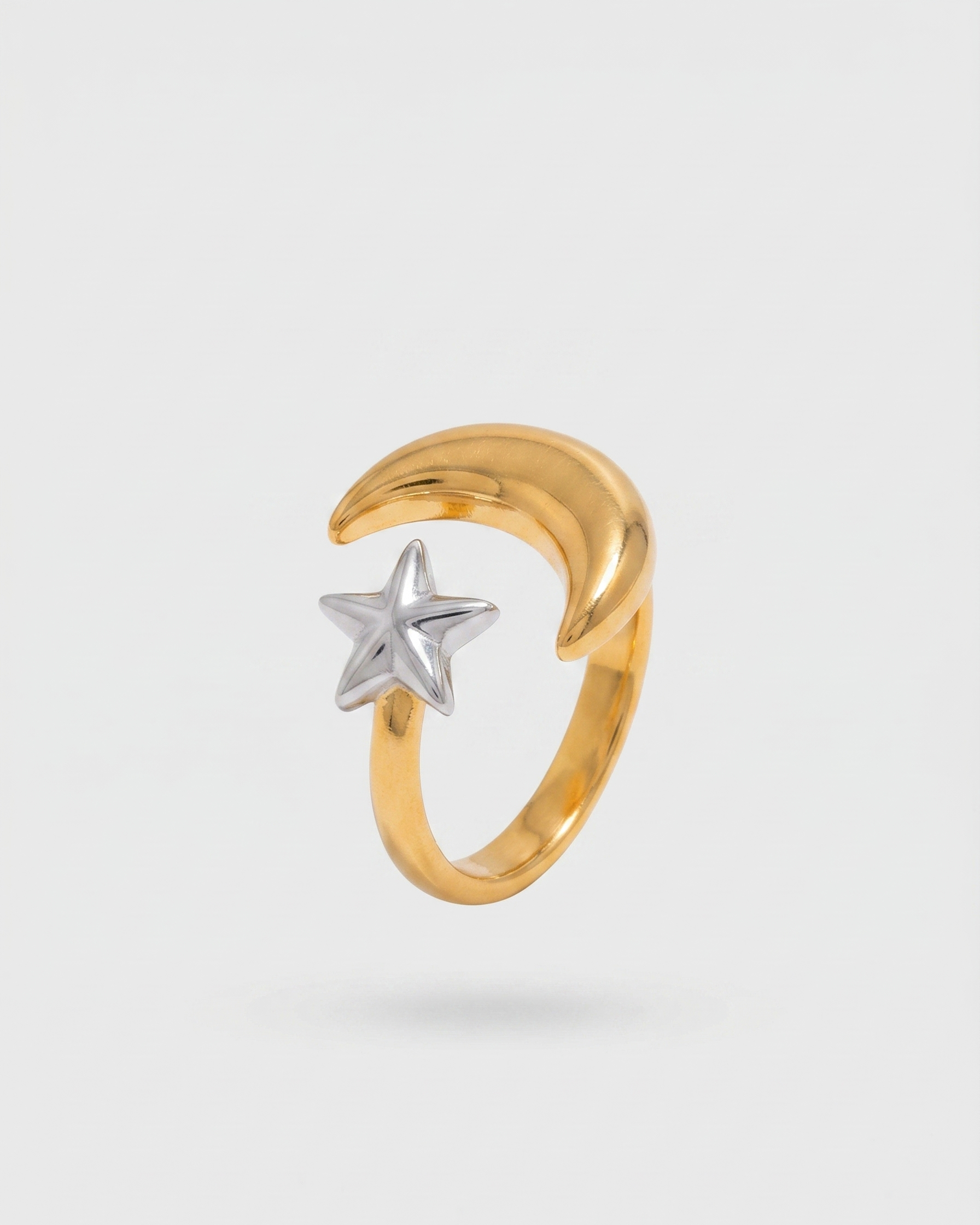 Gold ring with a star and moon design on a light gray background