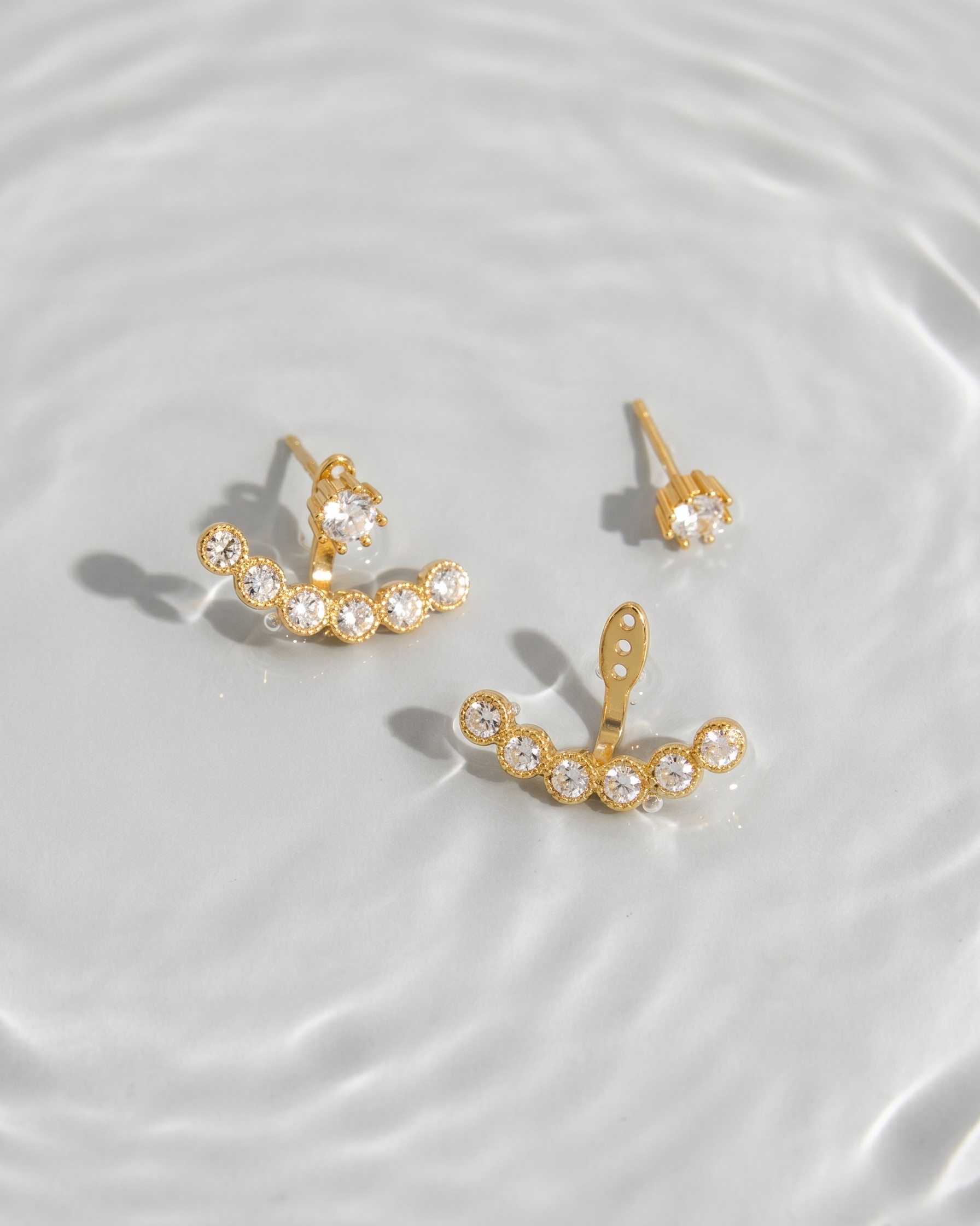 Gold earrings with clear stones on a white surface