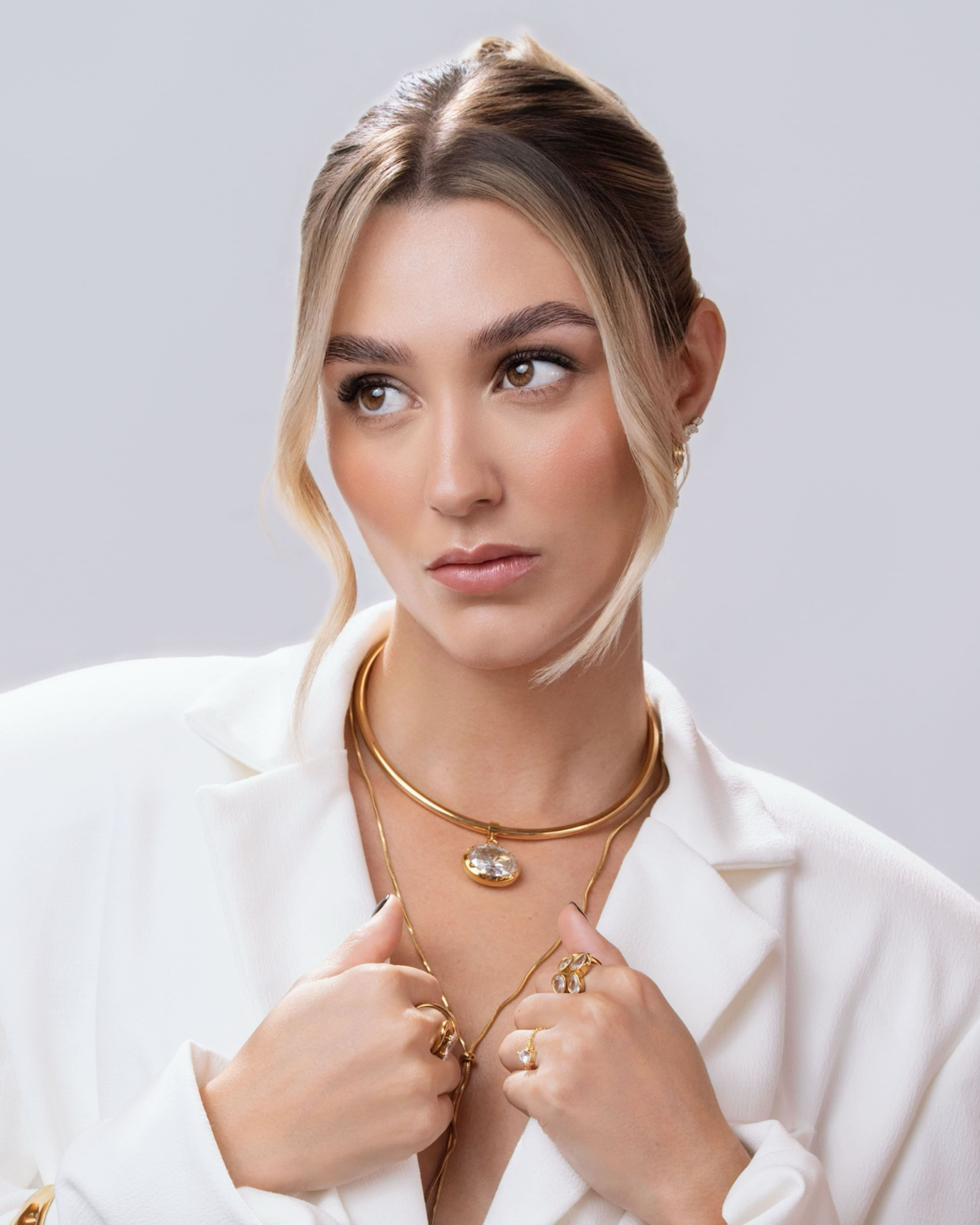 Woman wearing gold jewelry against a plain background