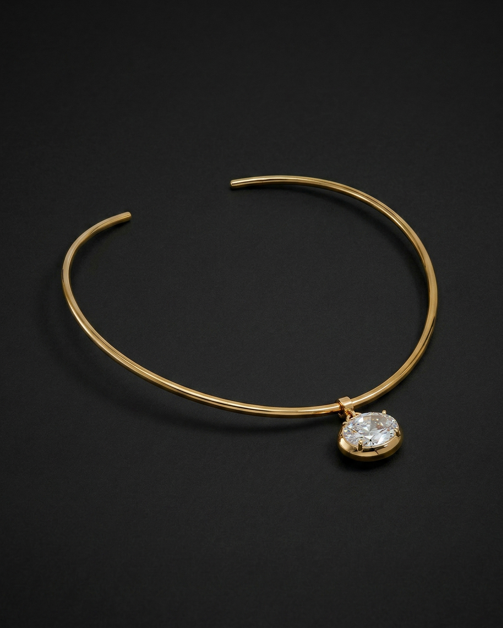 Gold bracelet with a diamond pendant on a dark background