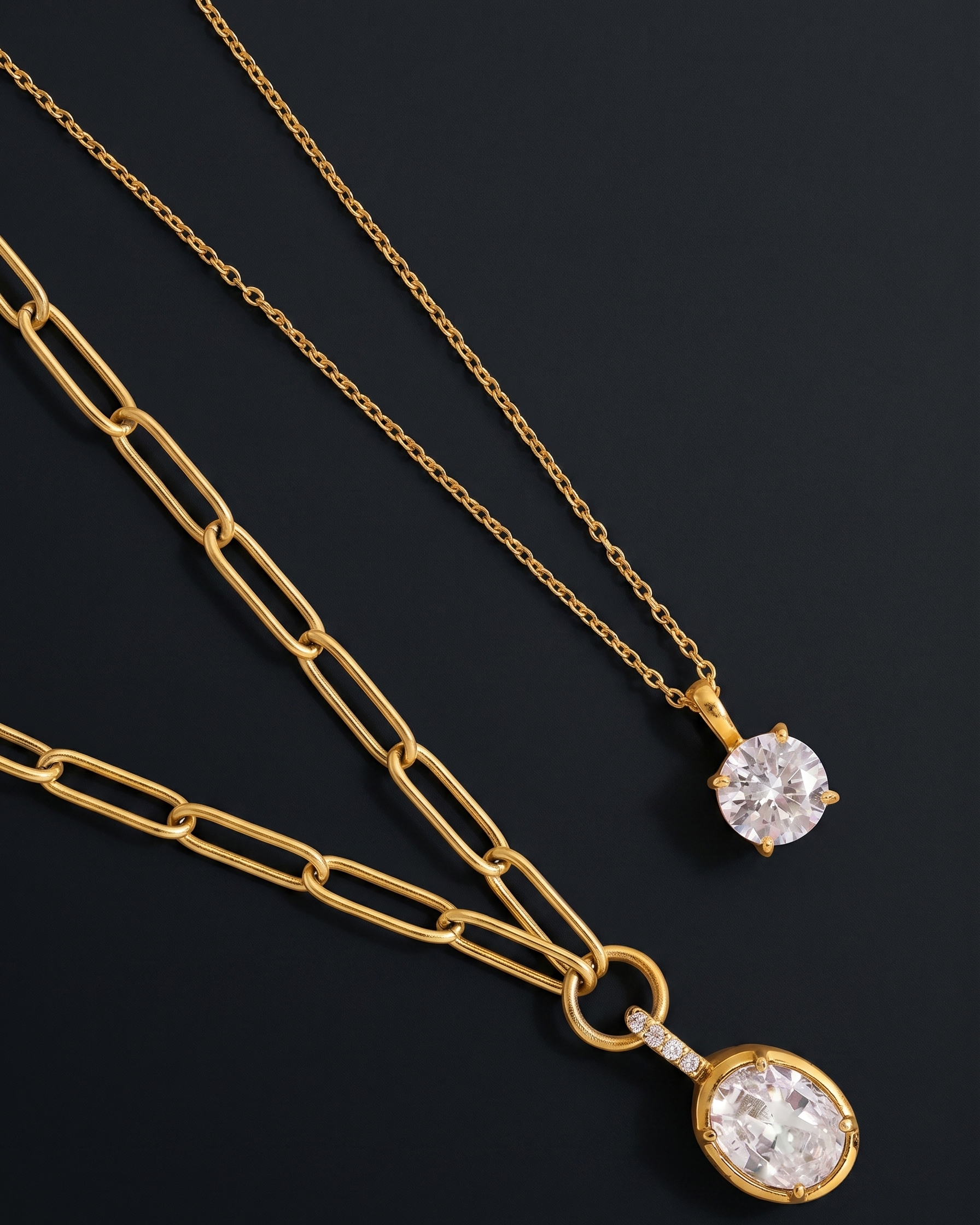 Two gold necklaces with diamond pendants on a dark background