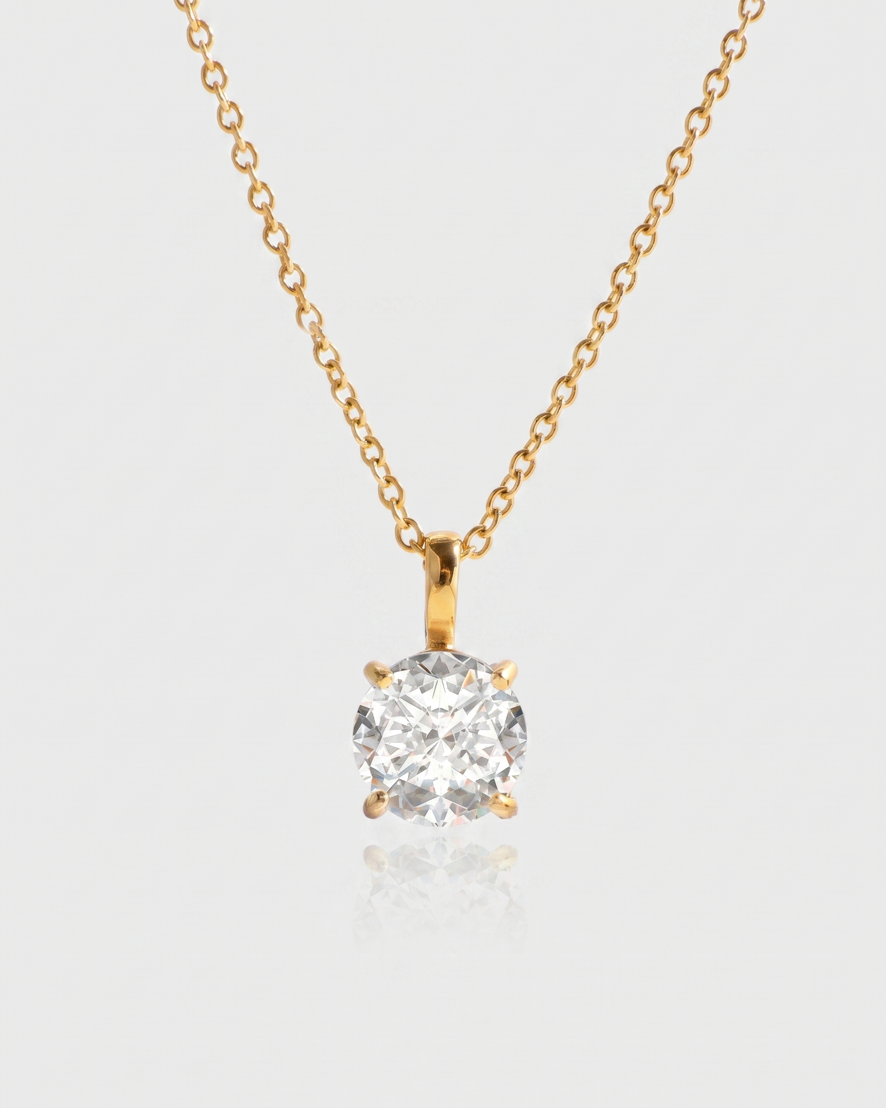 Gold necklace with a diamond pendant on a light gray background