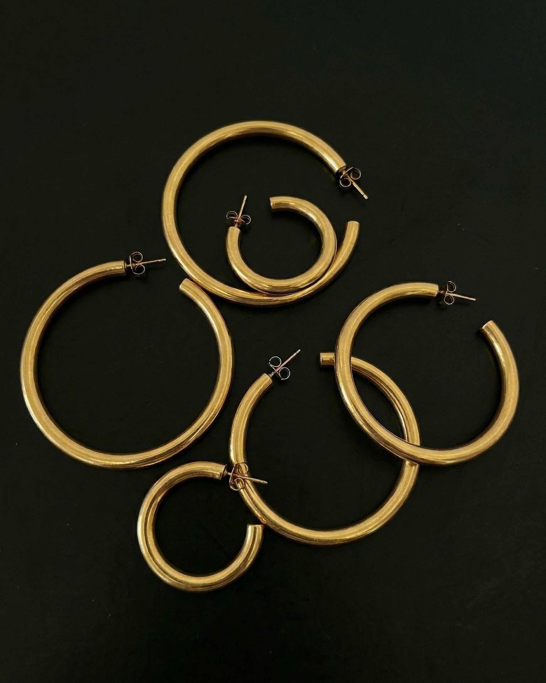 Set of gold hoop earrings on a black background