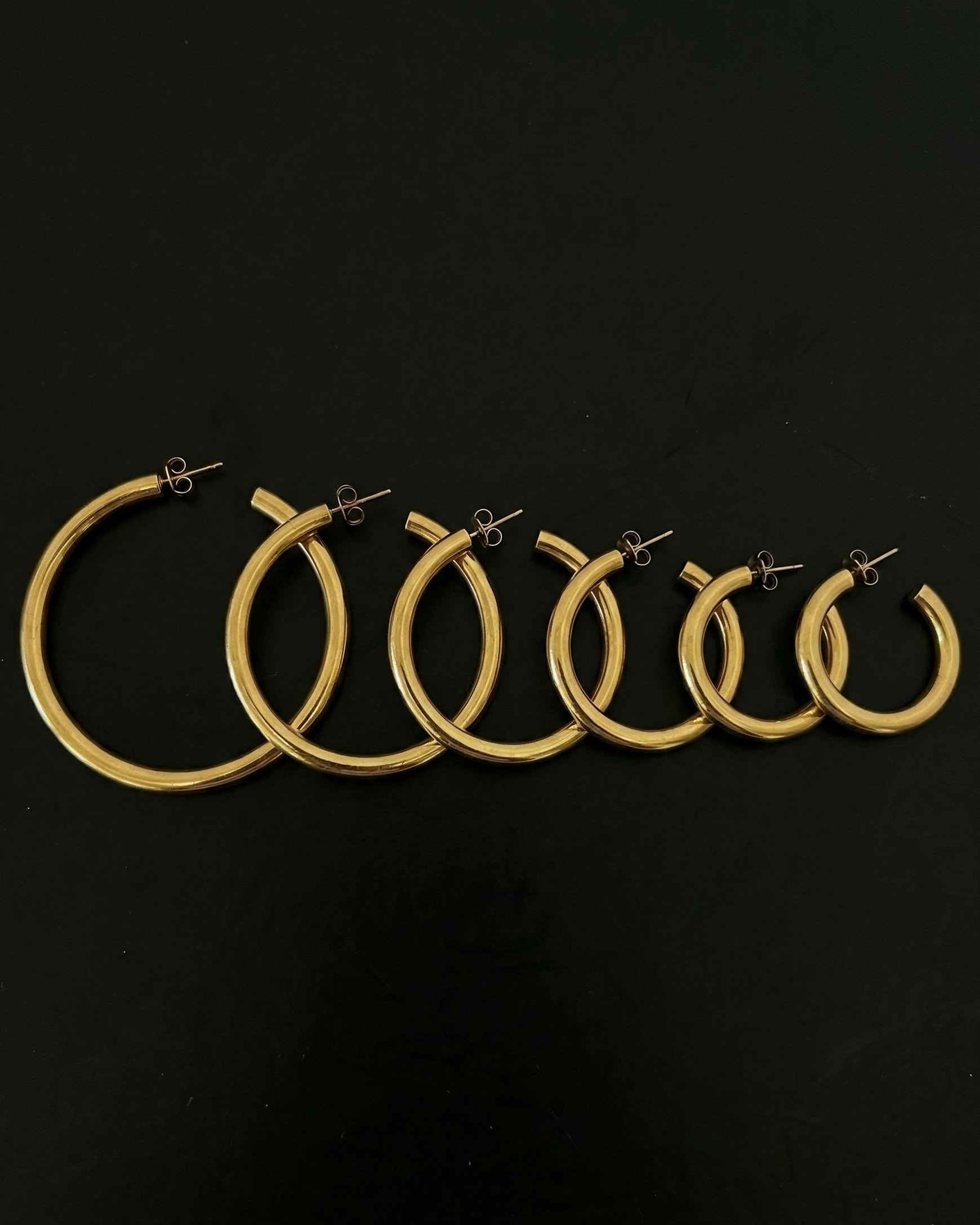 Set of gold hoop earrings on a black background