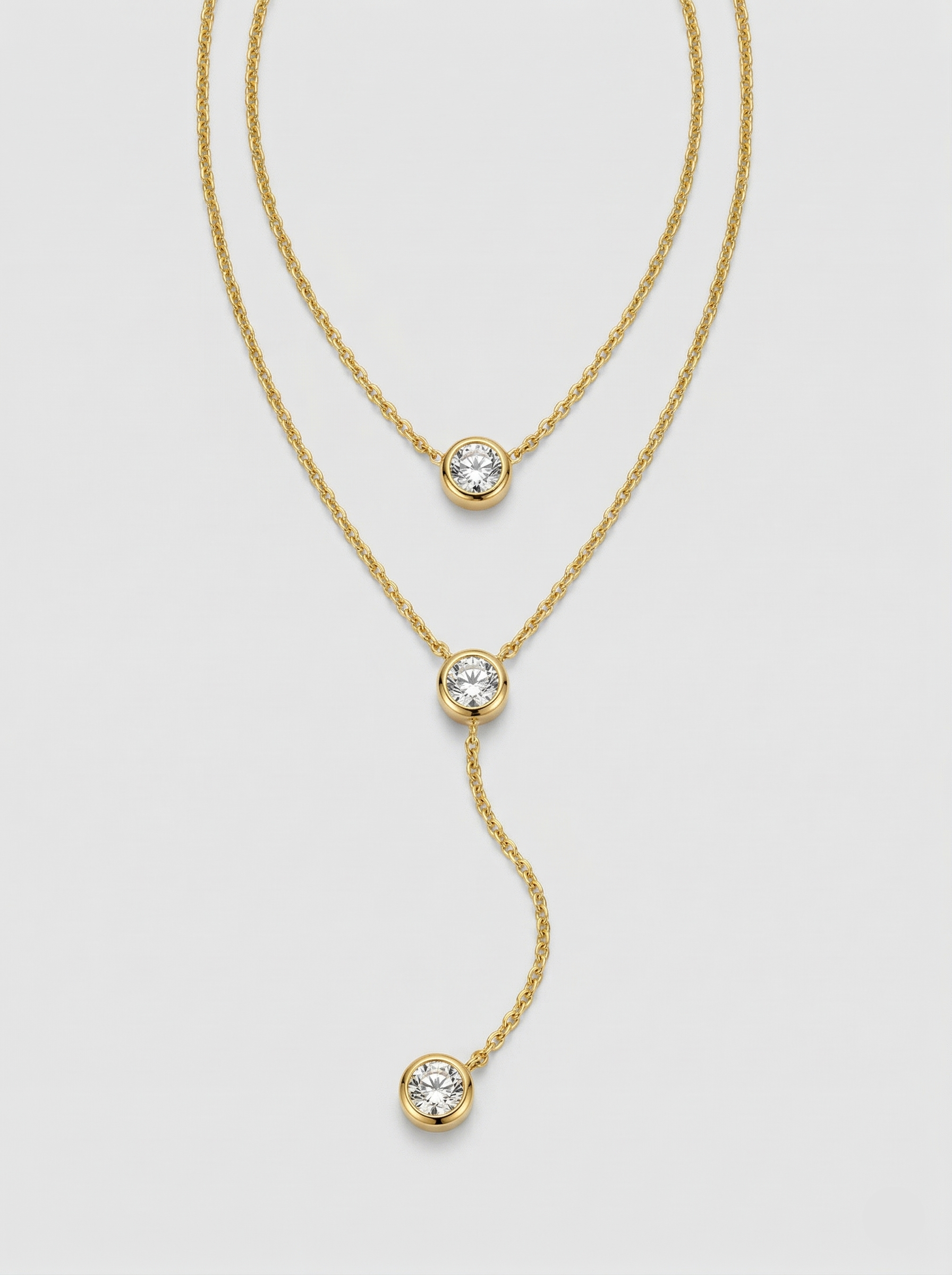 Gold necklace with diamond pendants on a light gray background