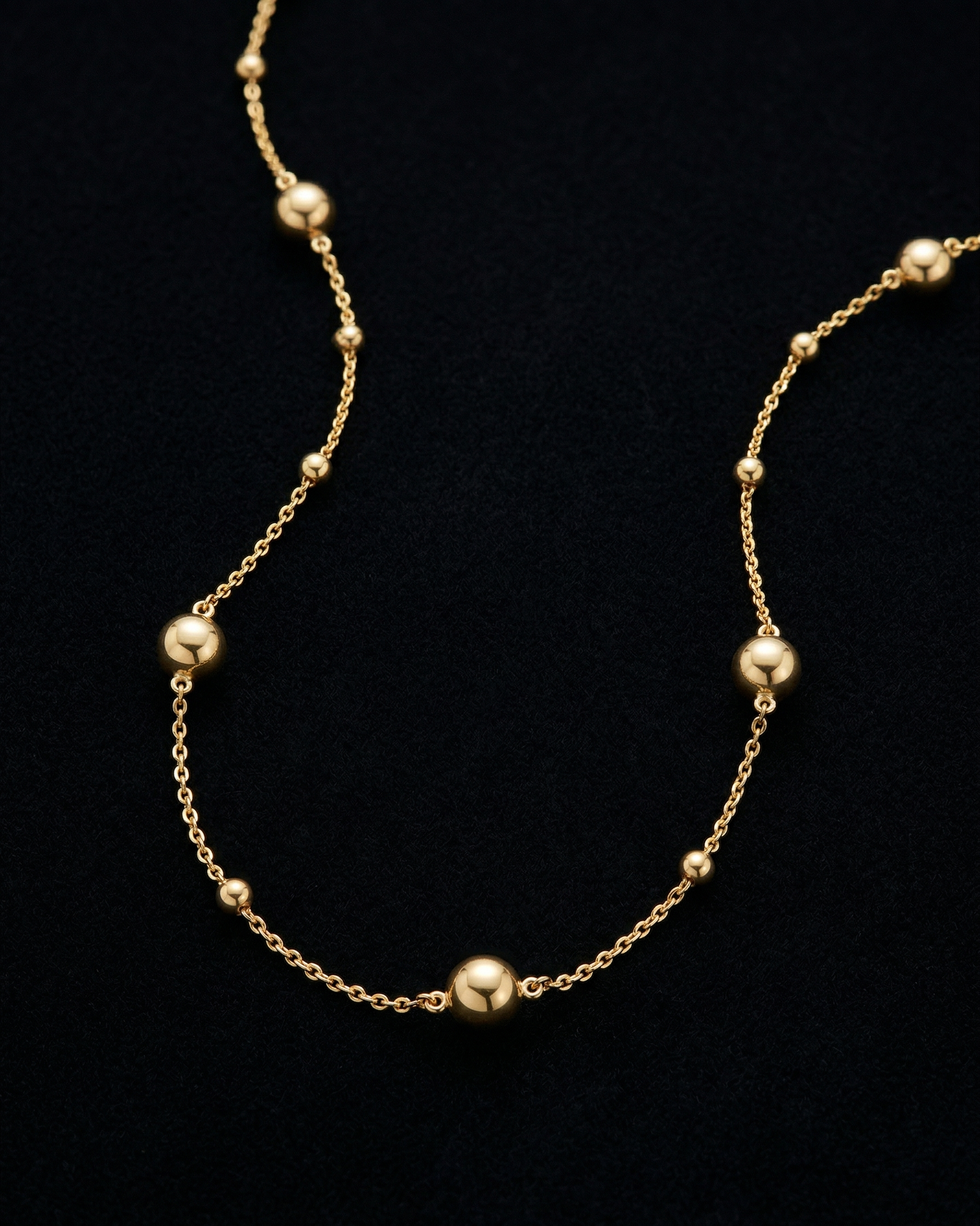 Gold necklace with small beads on a black background