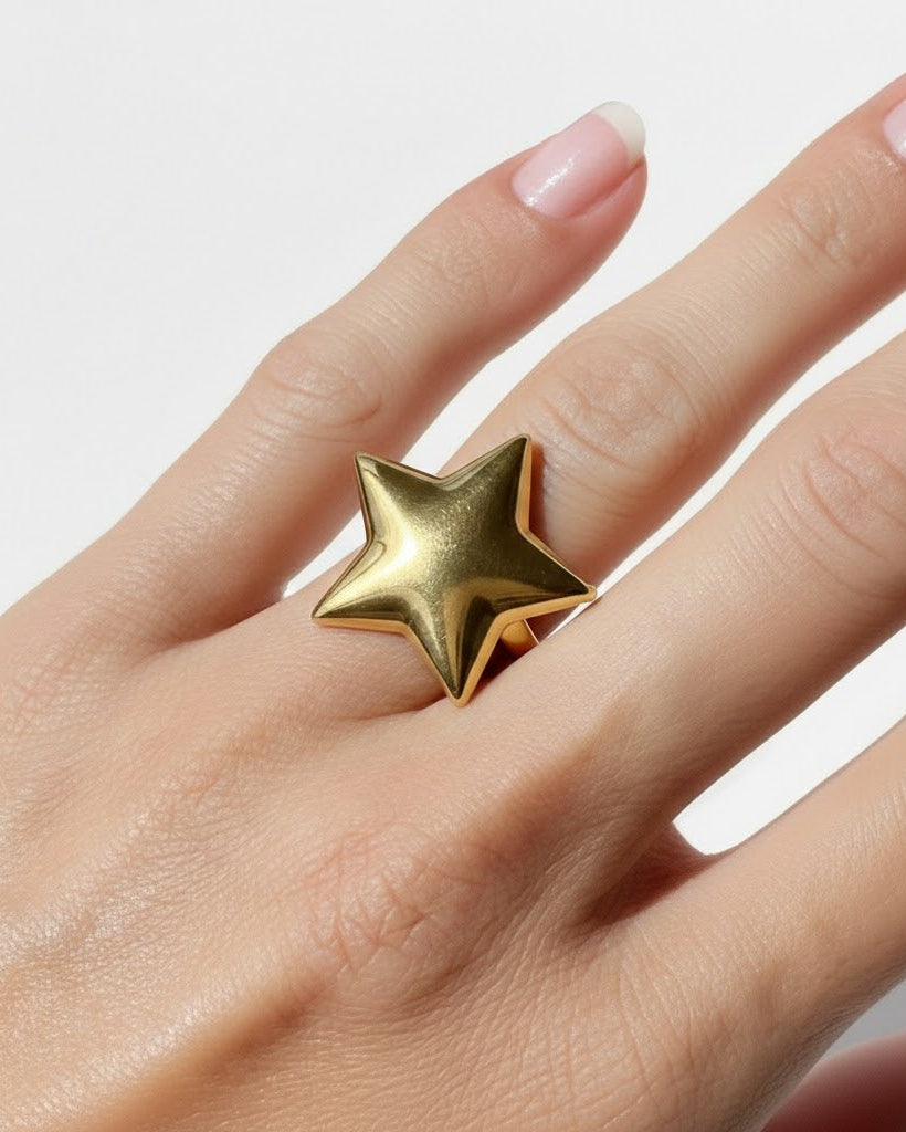 Gold star-shaped ring on a hand with a light background