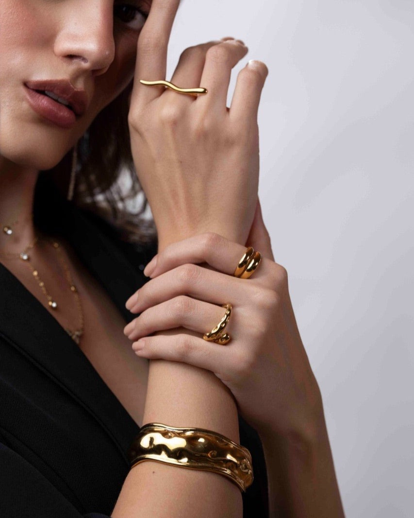 Close-up of a person wearing gold jewelry on a plain background