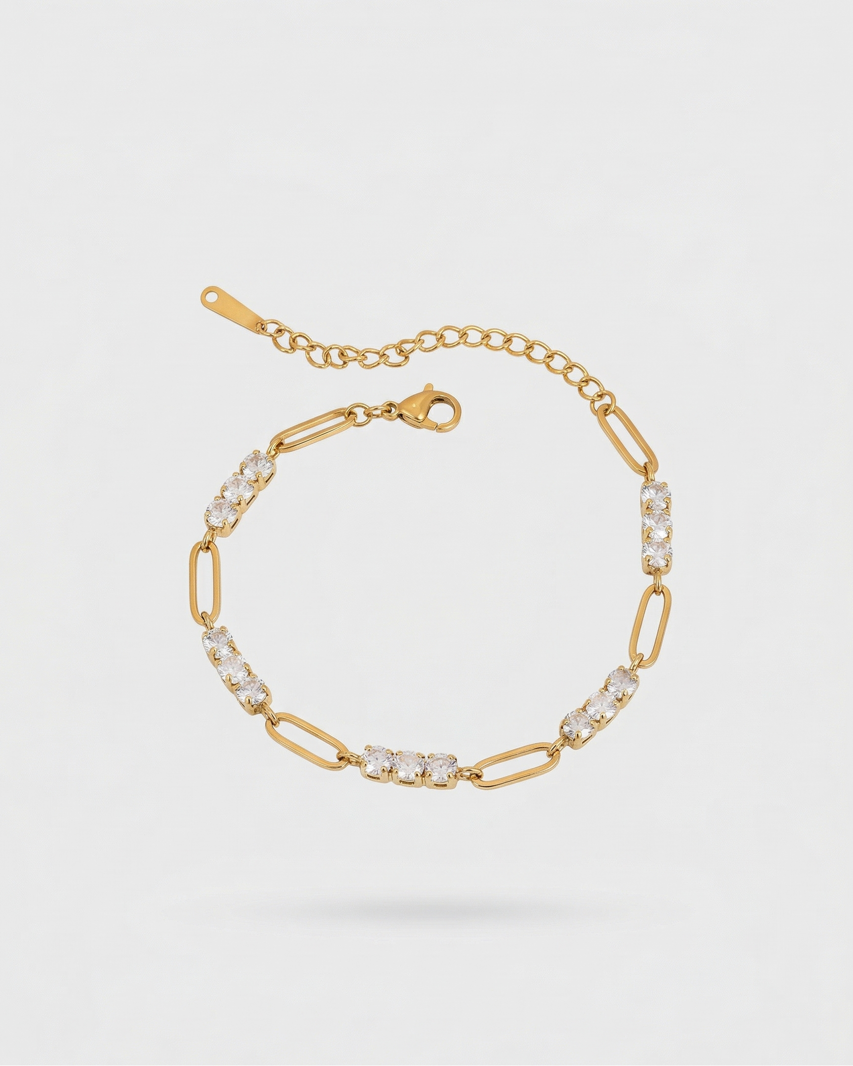 Gold bracelet with clear stones on a light gray background