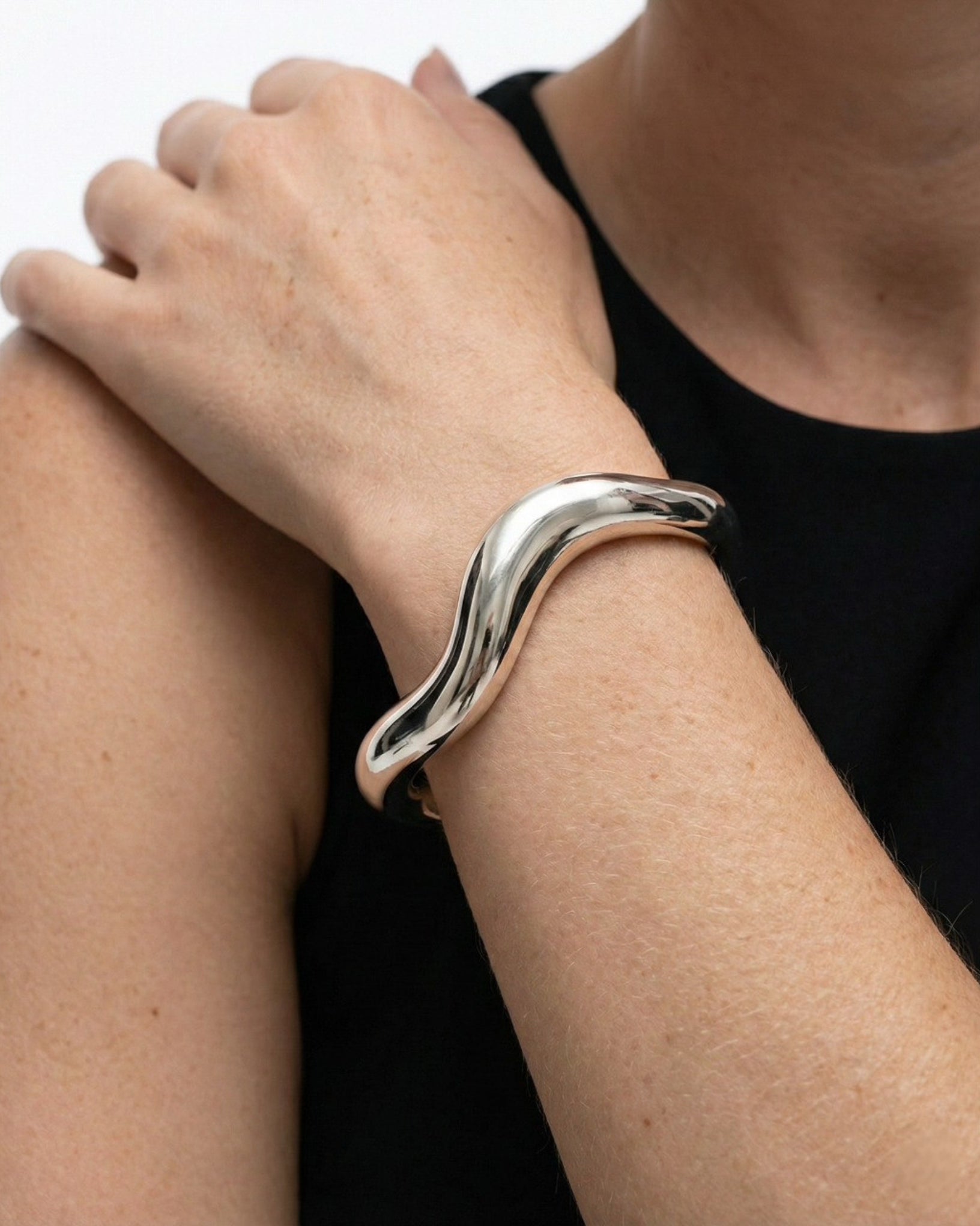 Silver bracelet on a wrist with a plain background
