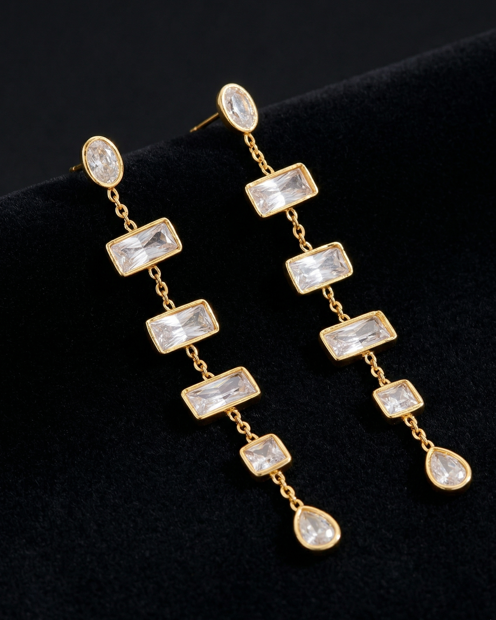 Gold earrings with clear gemstones on a black background