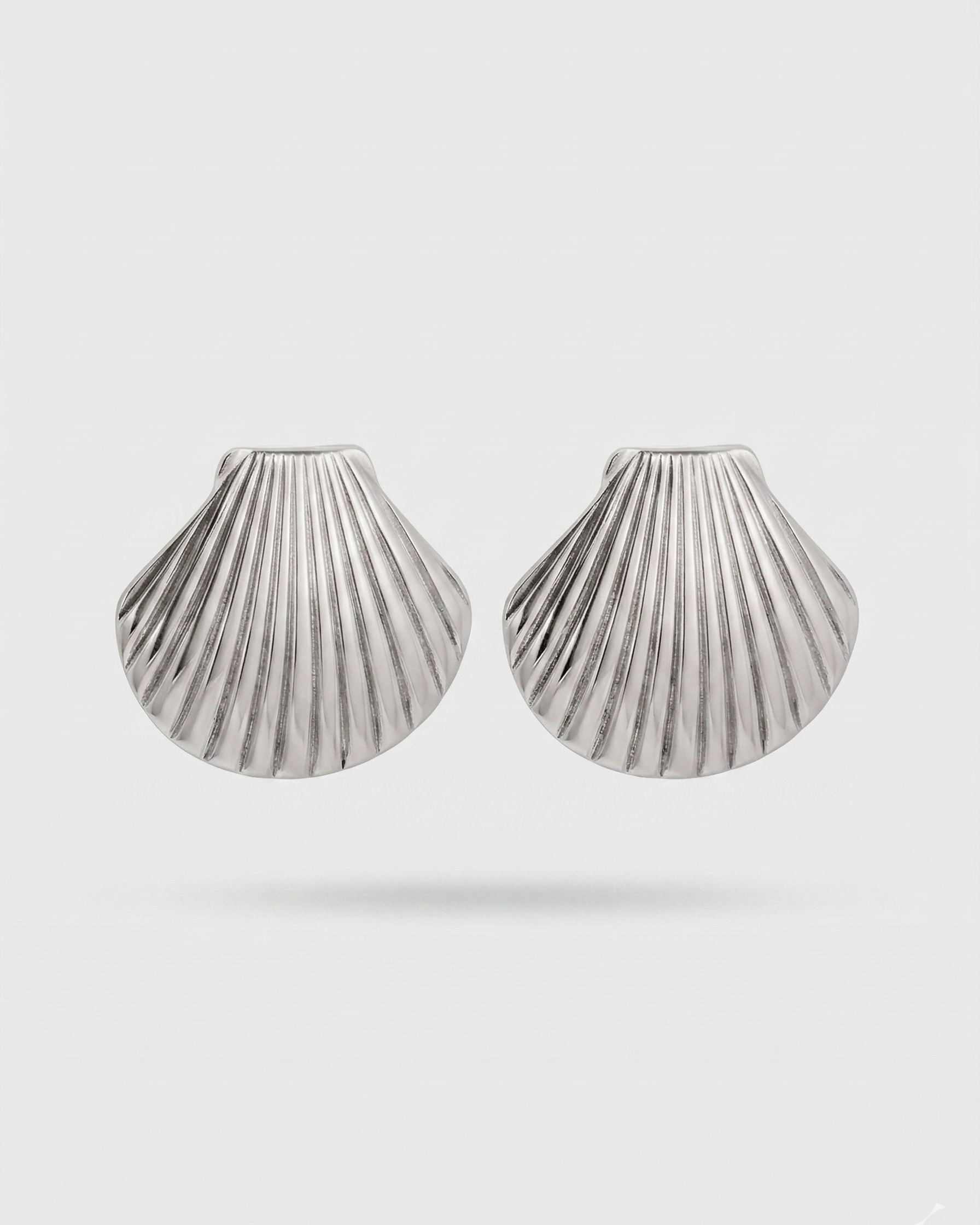 Pair of silver shell-shaped earrings on a light gray background