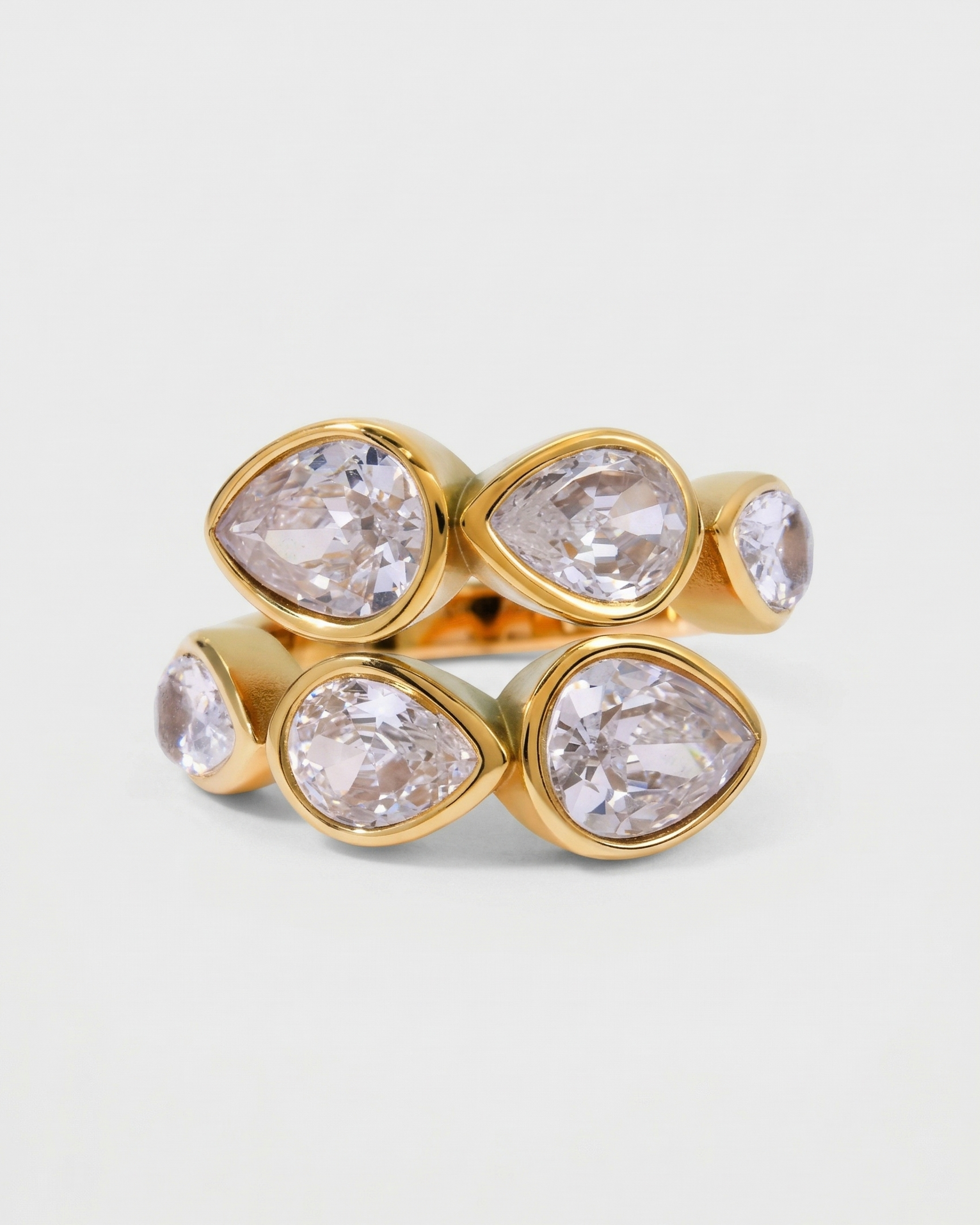 Gold ring with four large teardrop-shaped gemstones on a light gray background