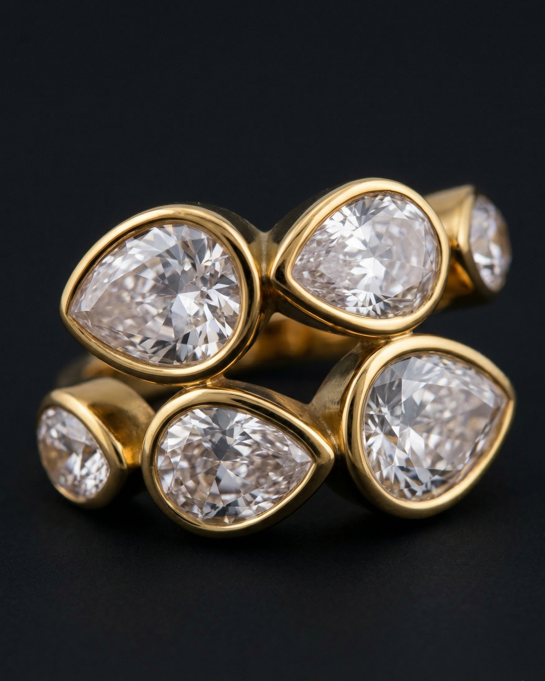 Gold ring with pear-shaped diamonds on a black background