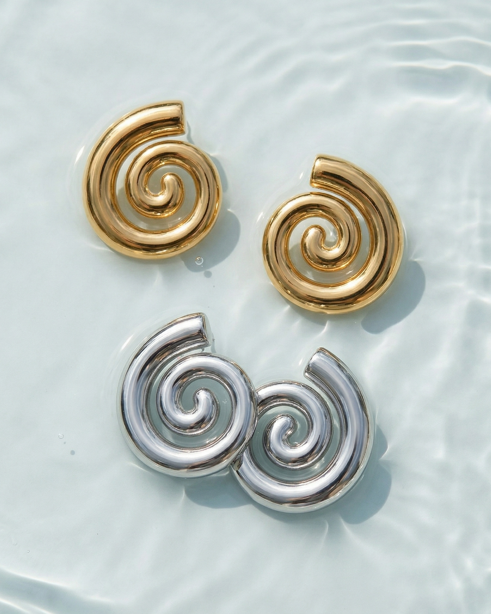 Pair of spiral-shaped earrings on a light blue water-like background