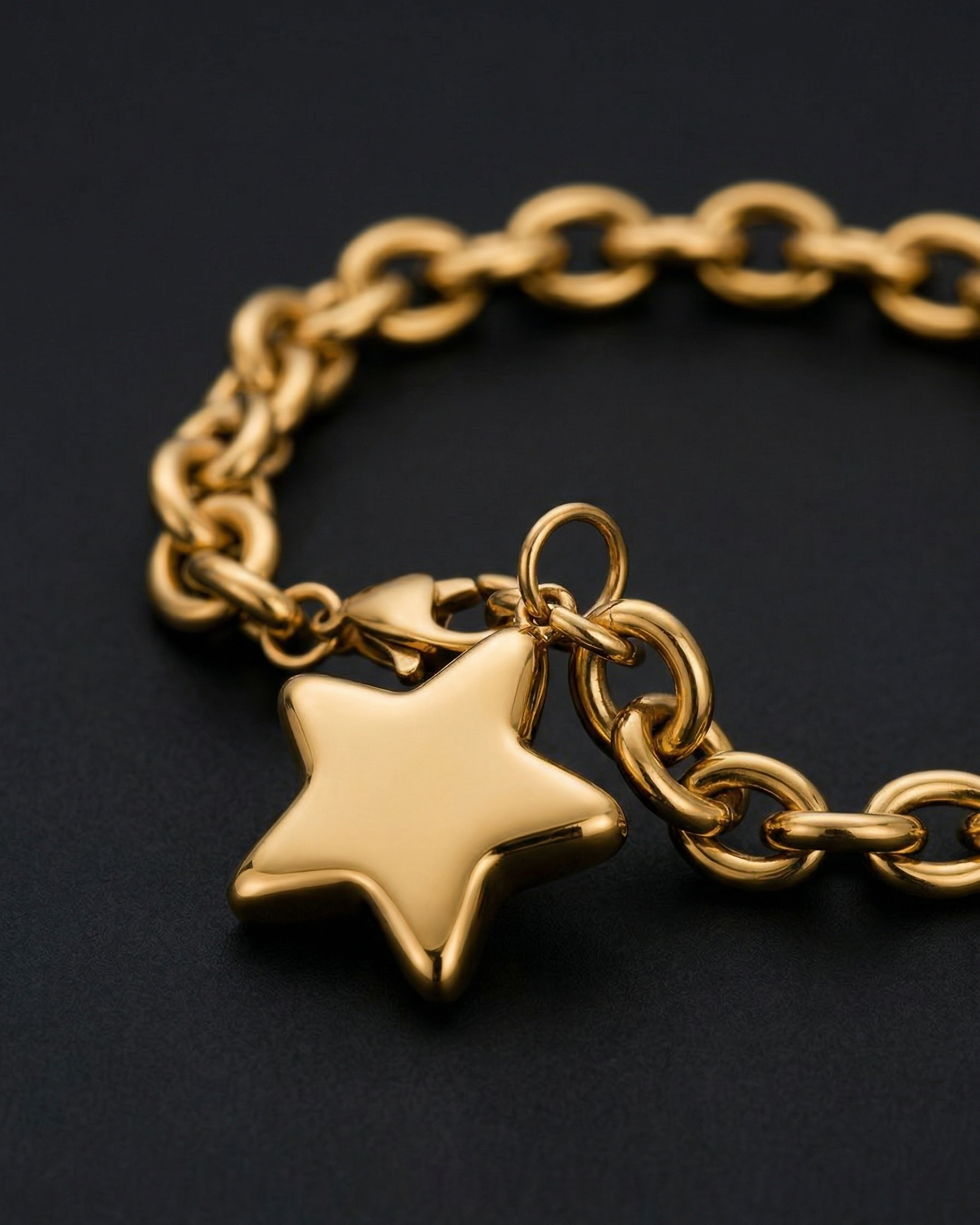 Gold chain bracelet with a star-shaped charm on a black background
