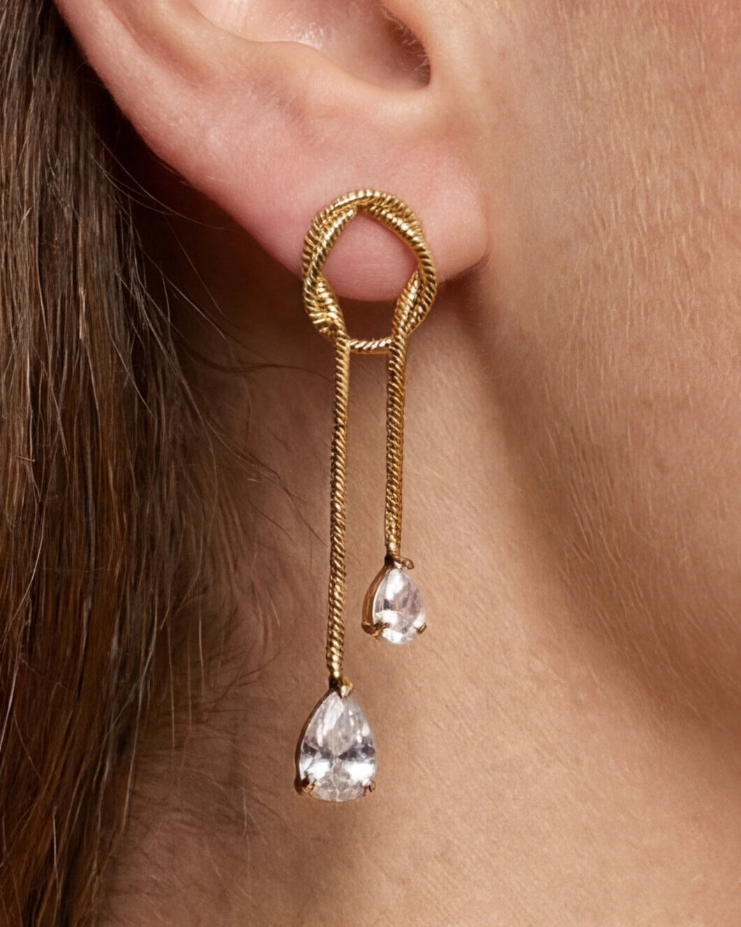 Gold earring with dangling crystals worn by a person