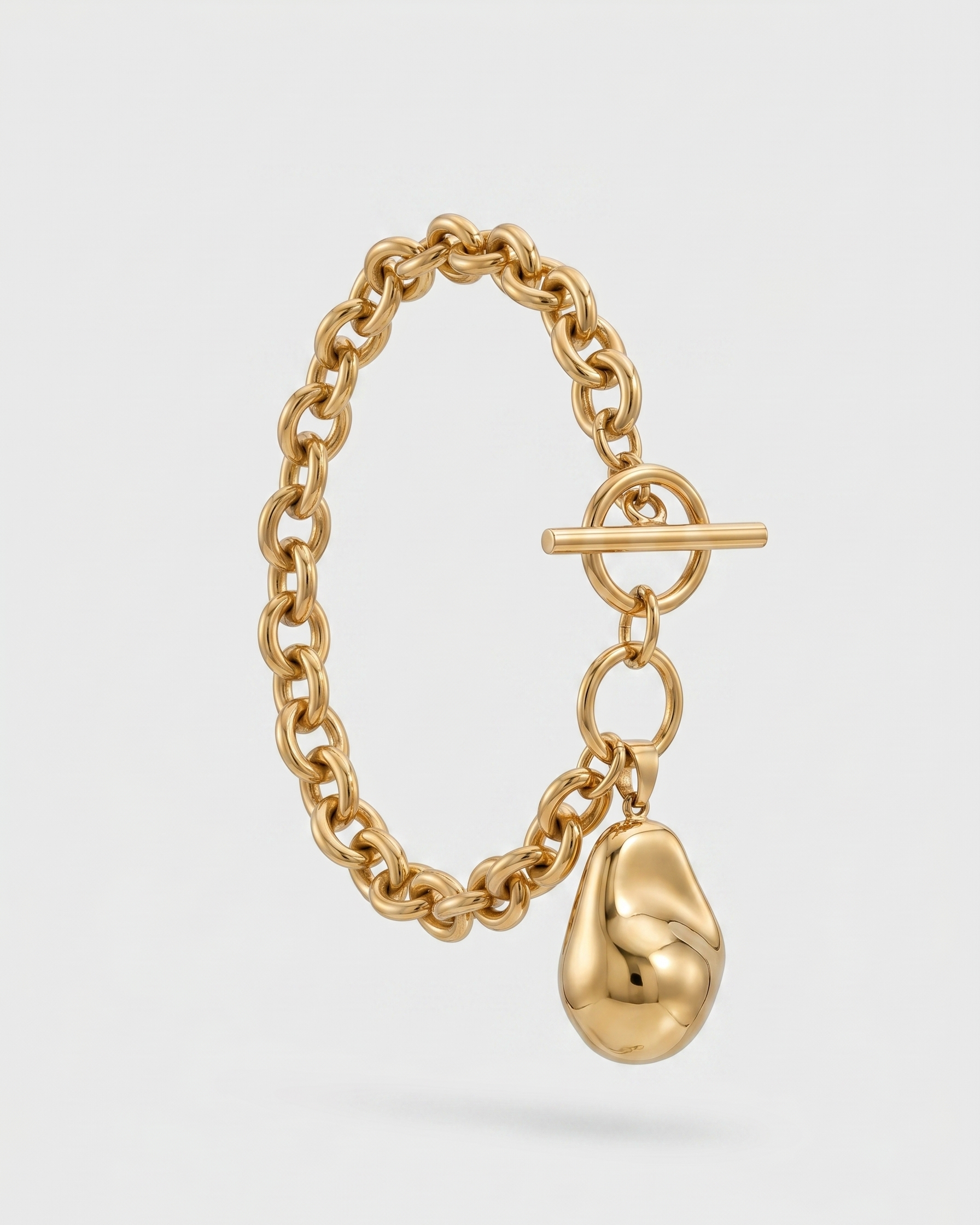 Gold chain bracelet with a unique pendant on a light gray background