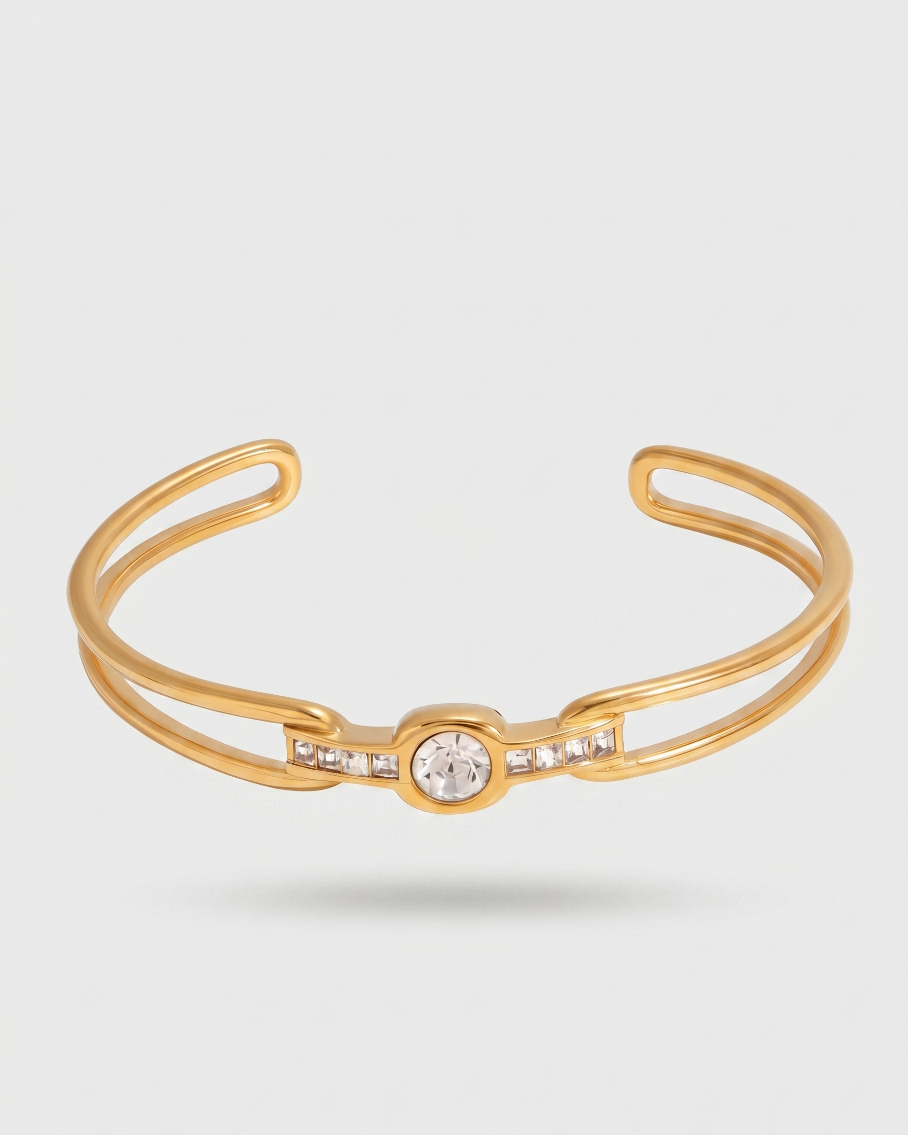 Gold bracelet with a central gemstone on a light gray background
