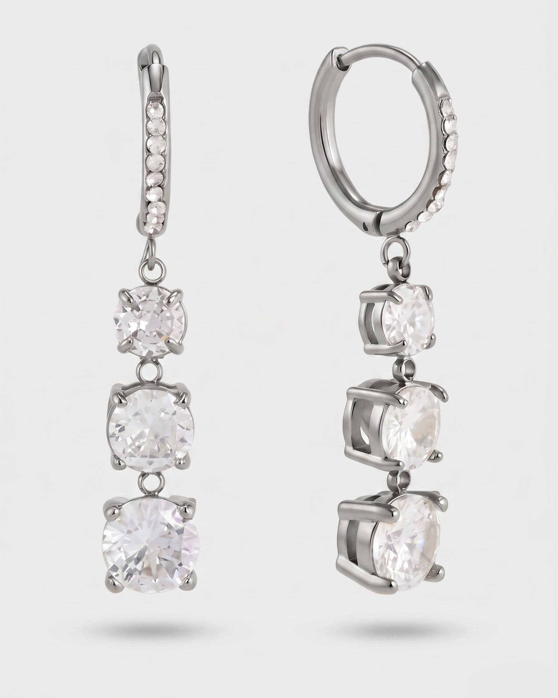 Pair of silver hoop earrings with clear gemstones on a light gray background