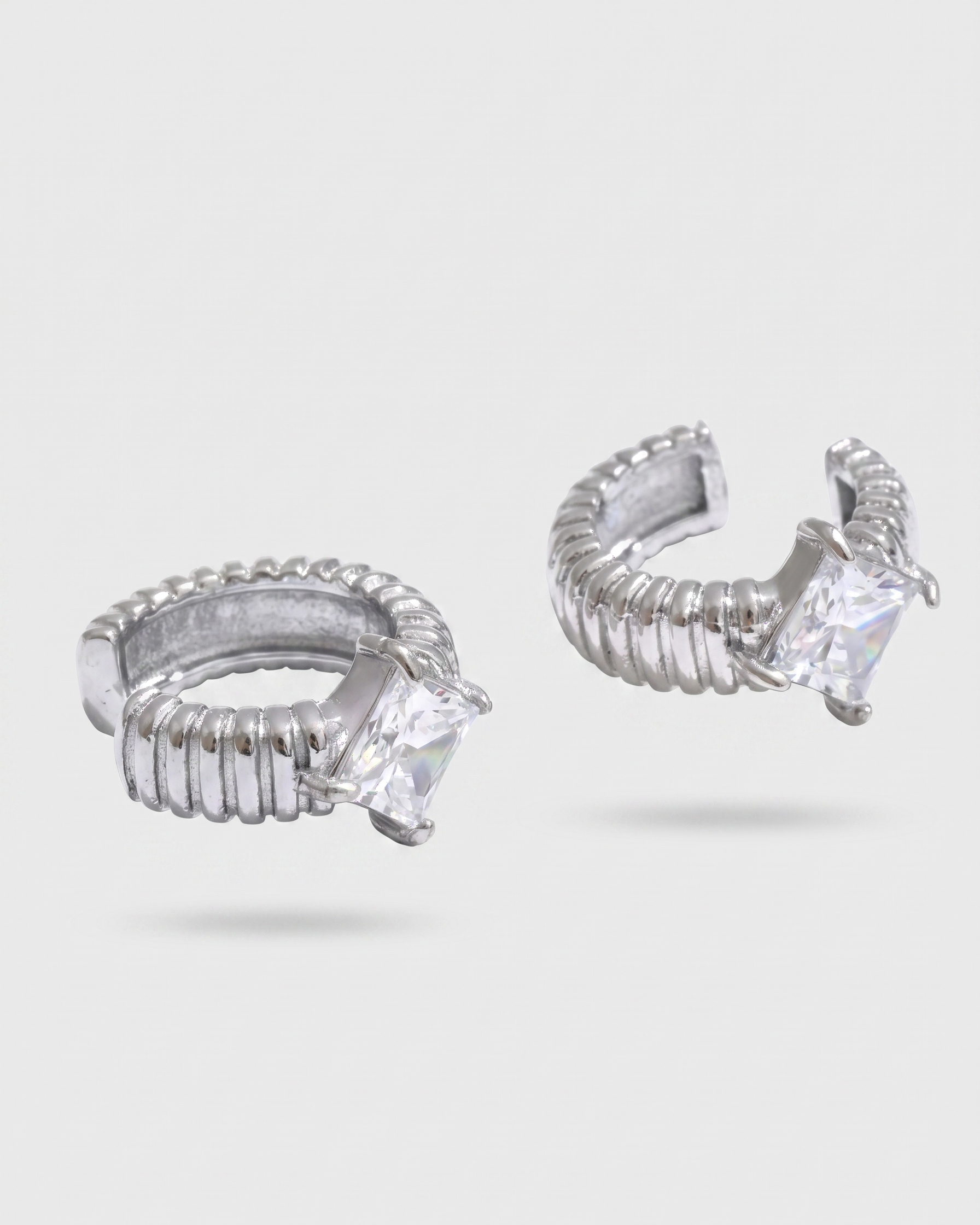 Silver hoop earrings with clear gemstones on a white background