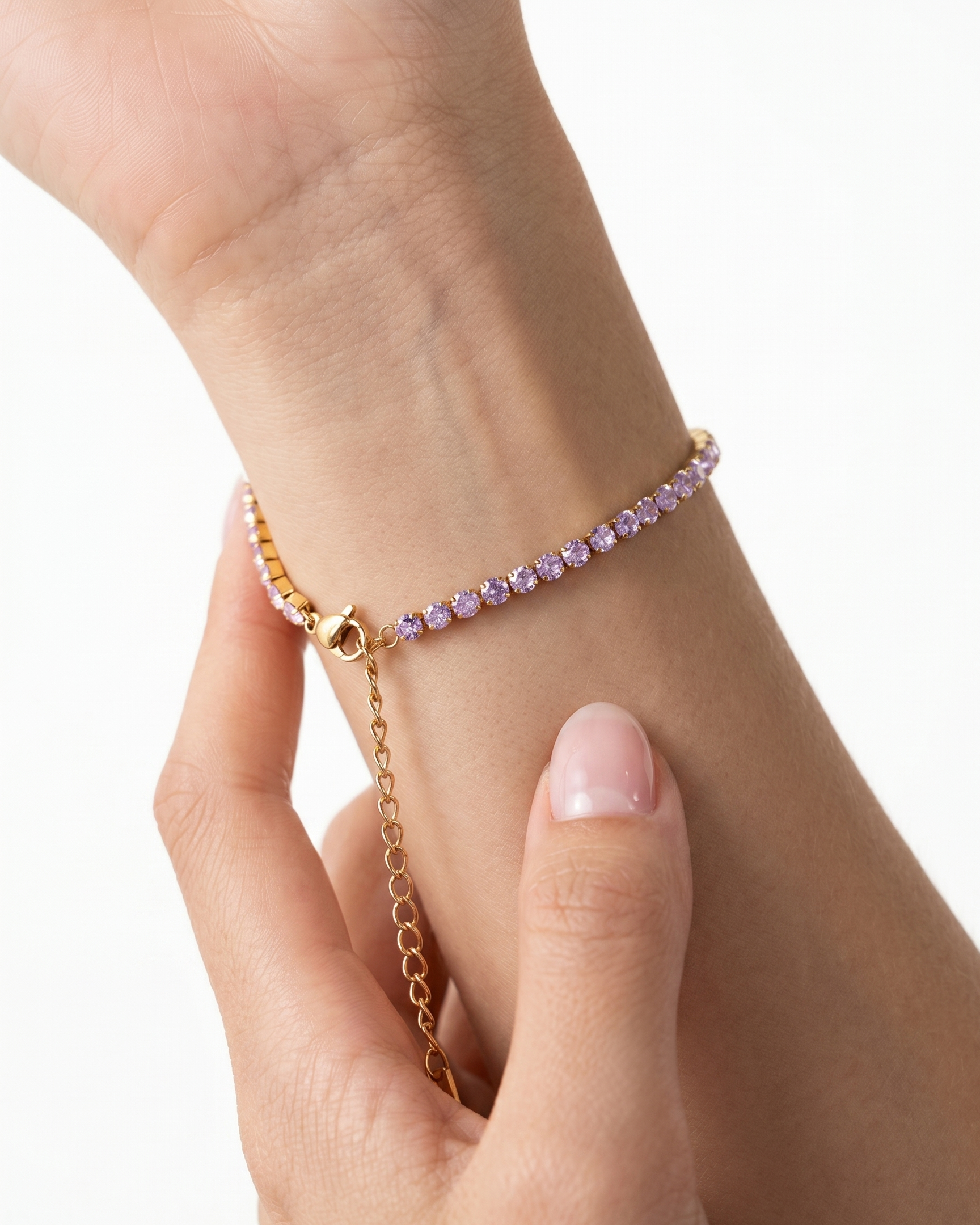 Gold bracelet with pink beads on a wrist against a white background