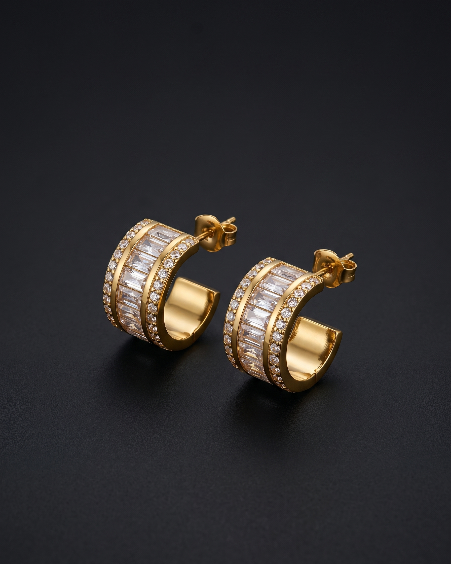 Gold hoop earrings with clear gemstones on a black background