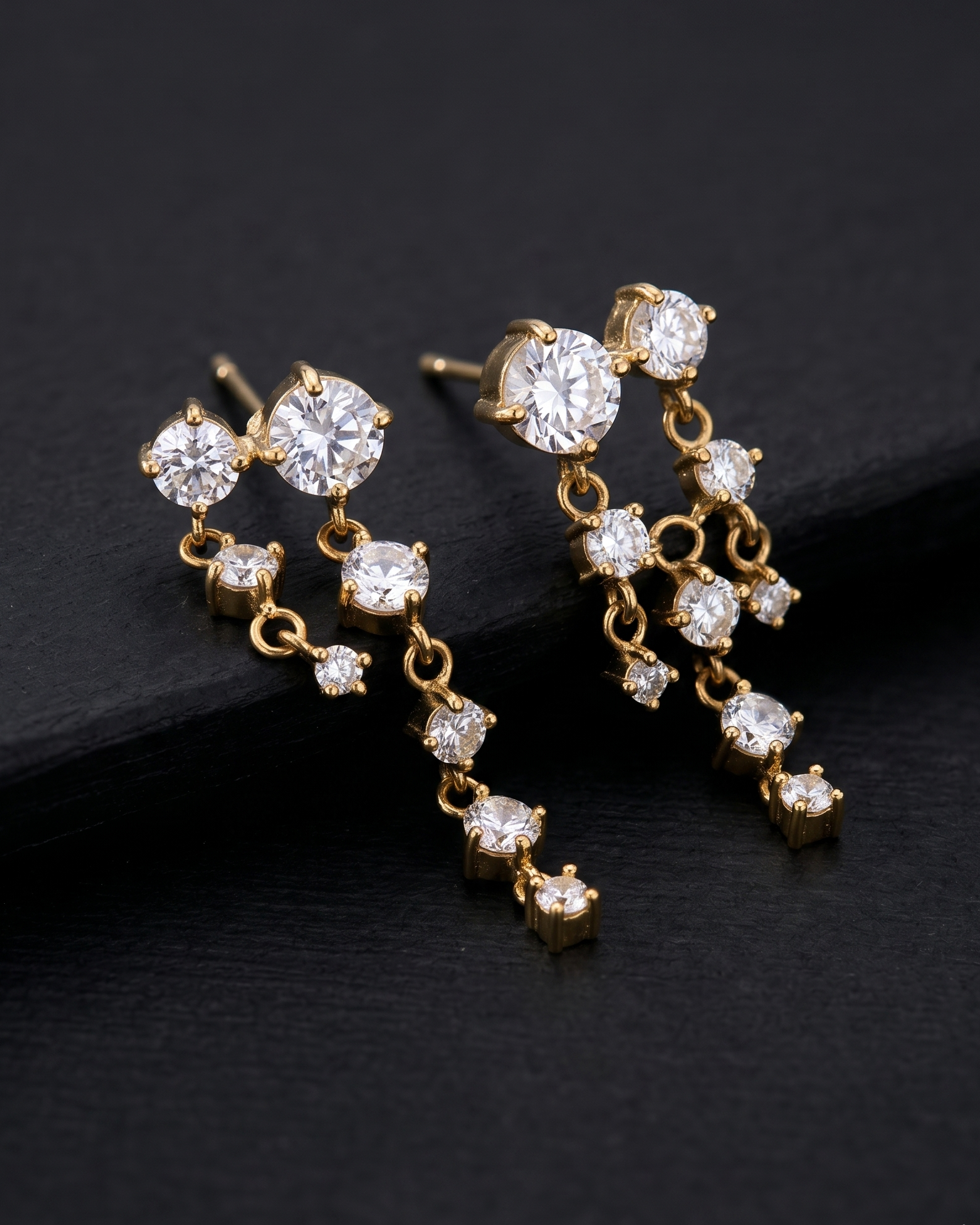Pair of gold earrings with clear gemstones on a dark background