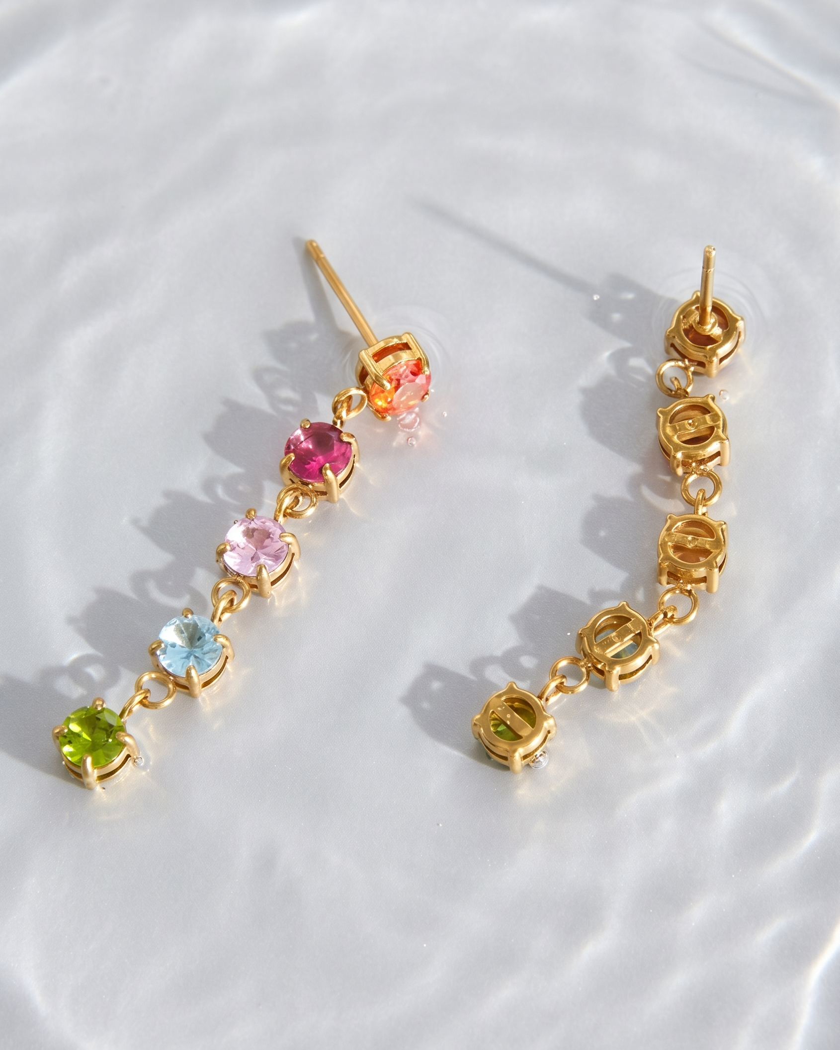Gold earrings with colorful gemstones on a white background