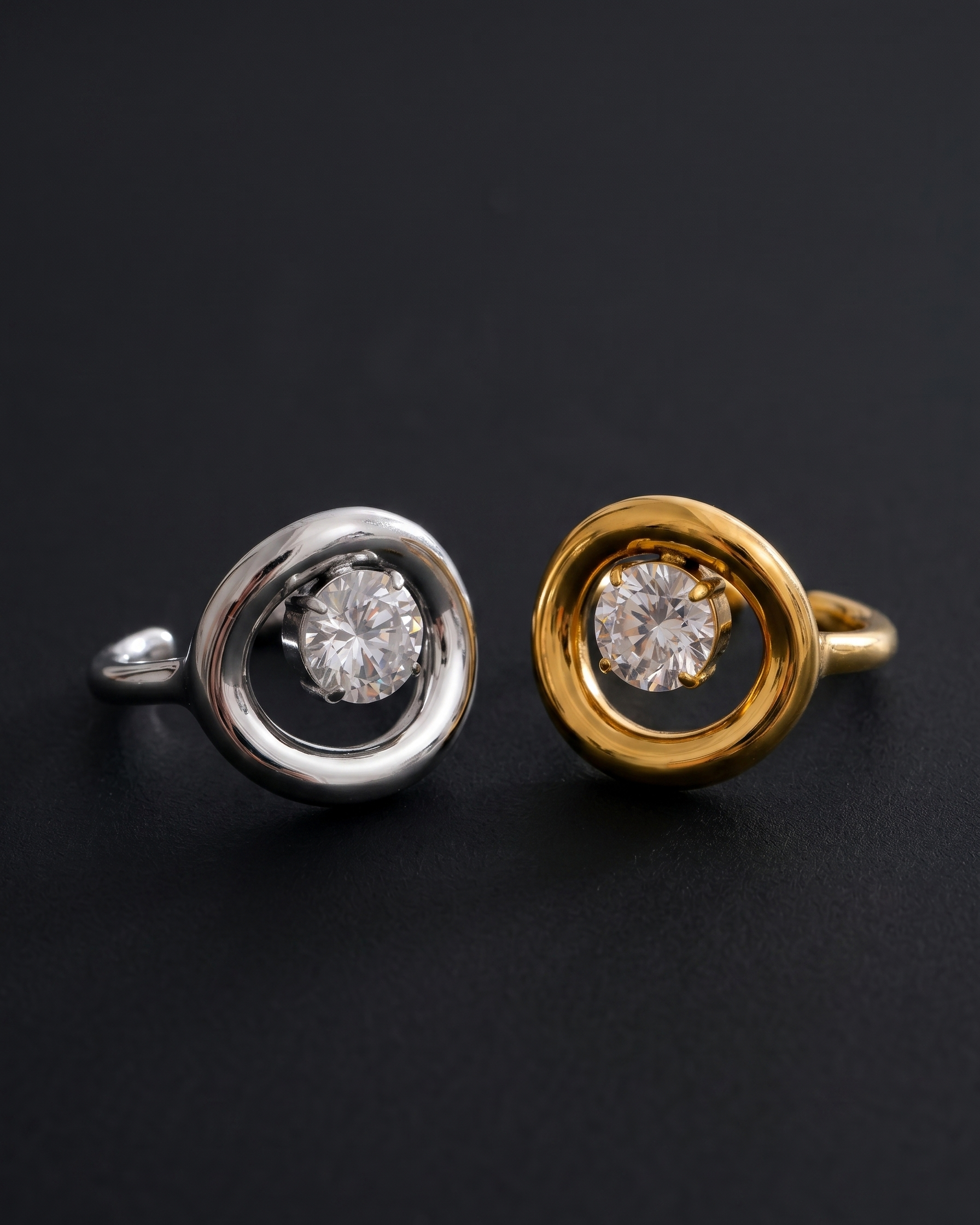Two rings, one silver and one gold, each with a central diamond on a black background.