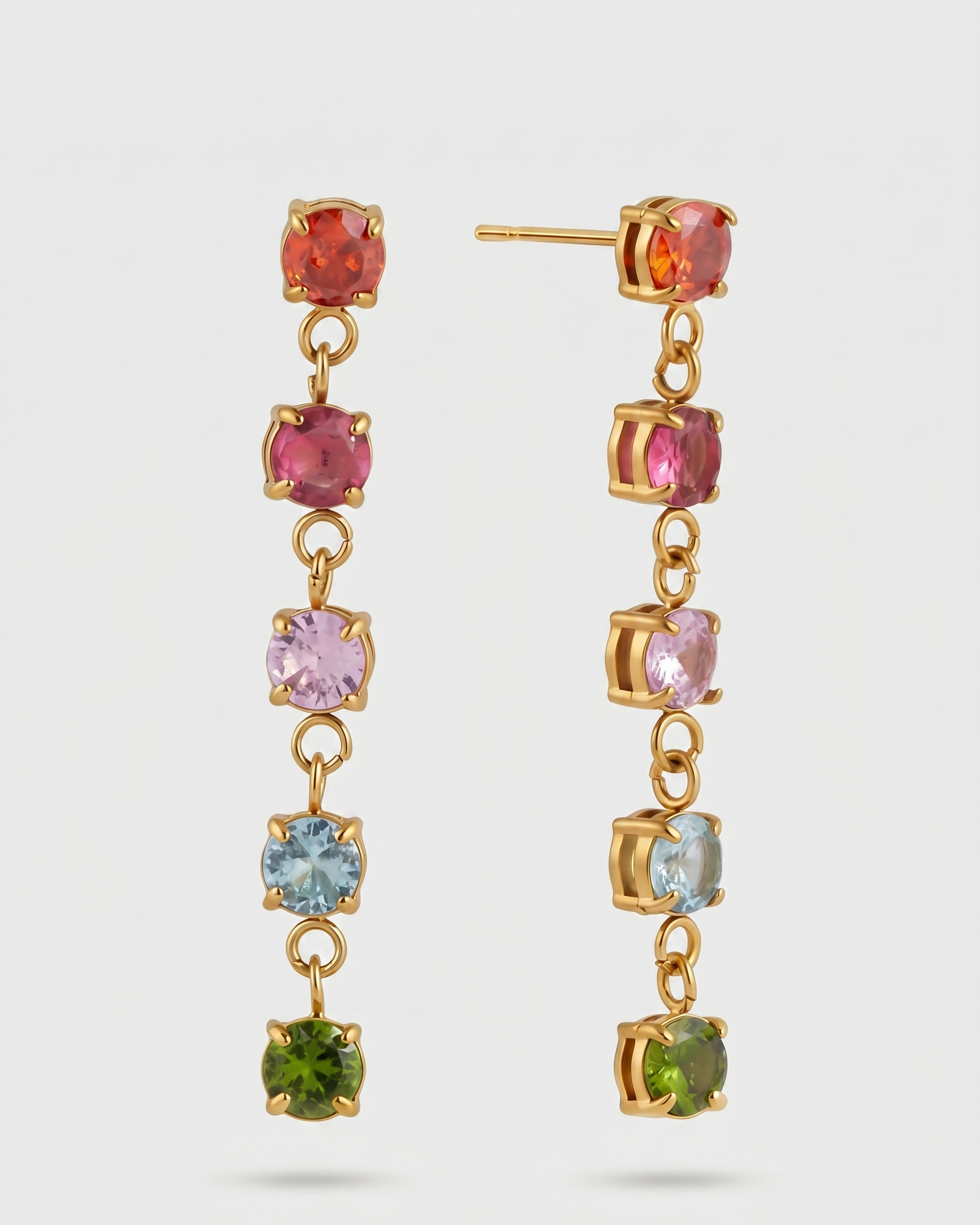 Pair of gold earrings with multicolored gemstones on a white background