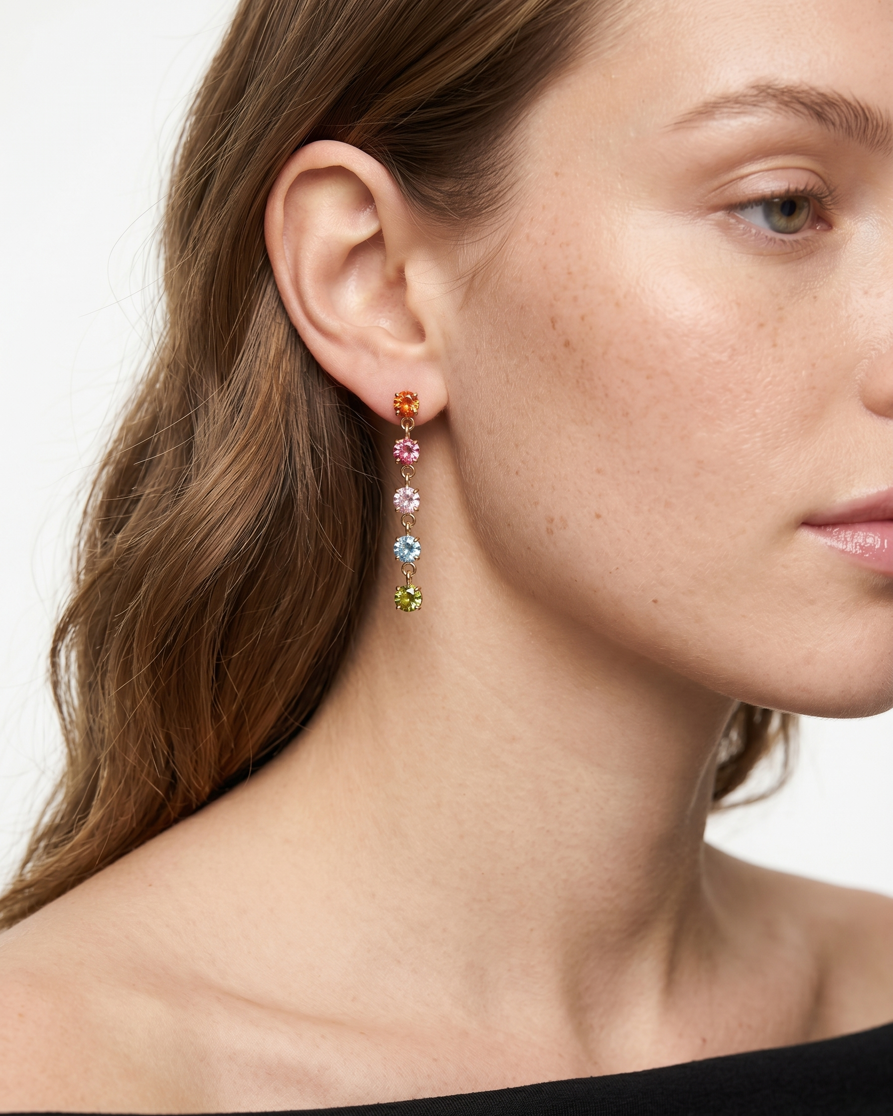 Close-up of a woman wearing colorful drop earrings with a neutral background