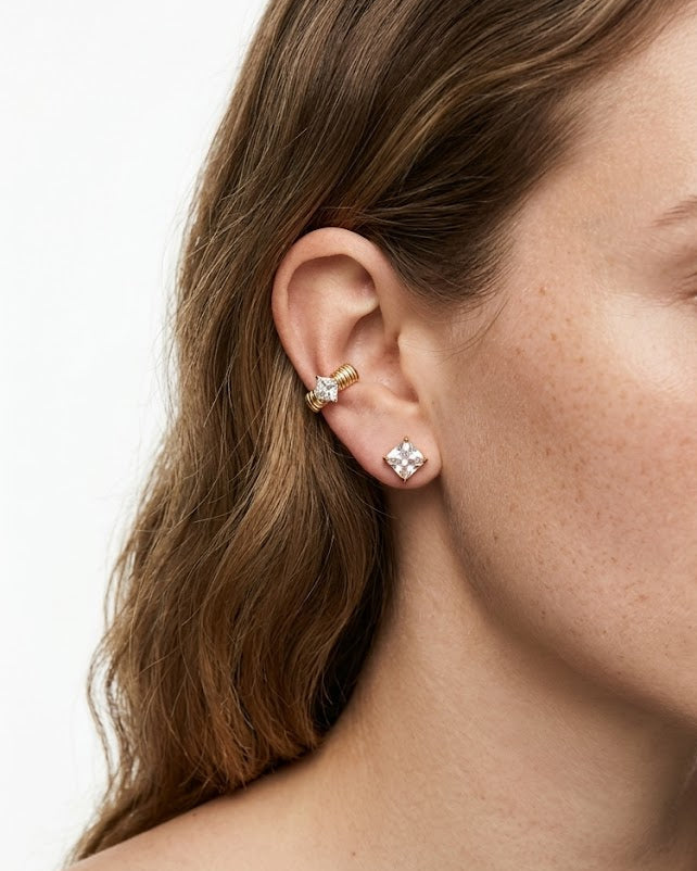 Close-up of a woman wearing diamond stud earrings on a white background