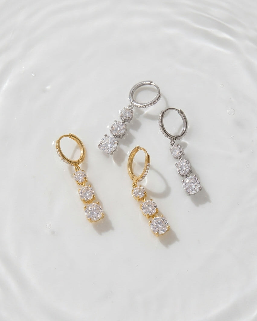 Pair of gold and silver earrings on a white surface